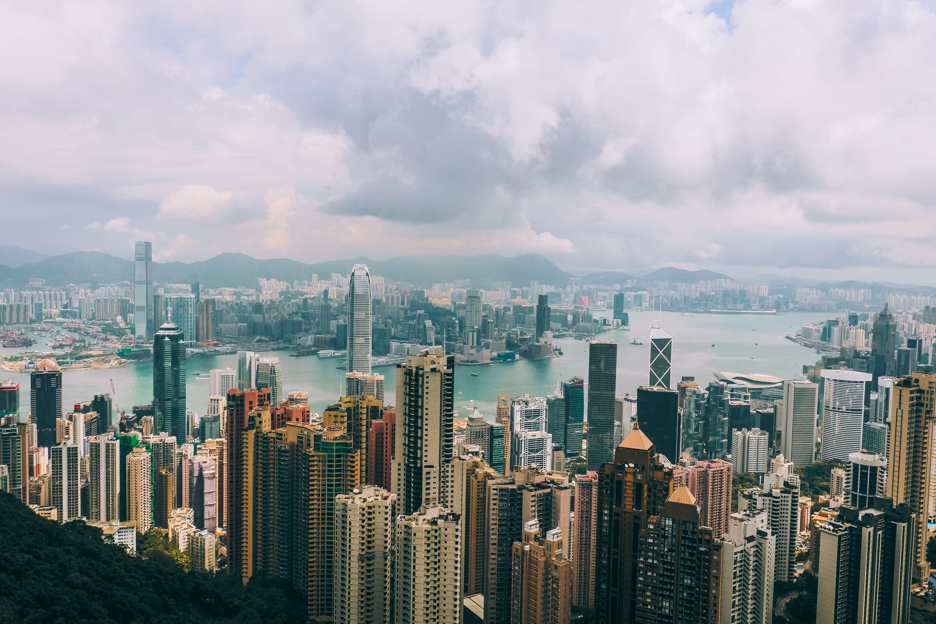 Sweeping daytime panoramic view from Victoria Peak looking down over dense skyscrapers and Victoria Harbour