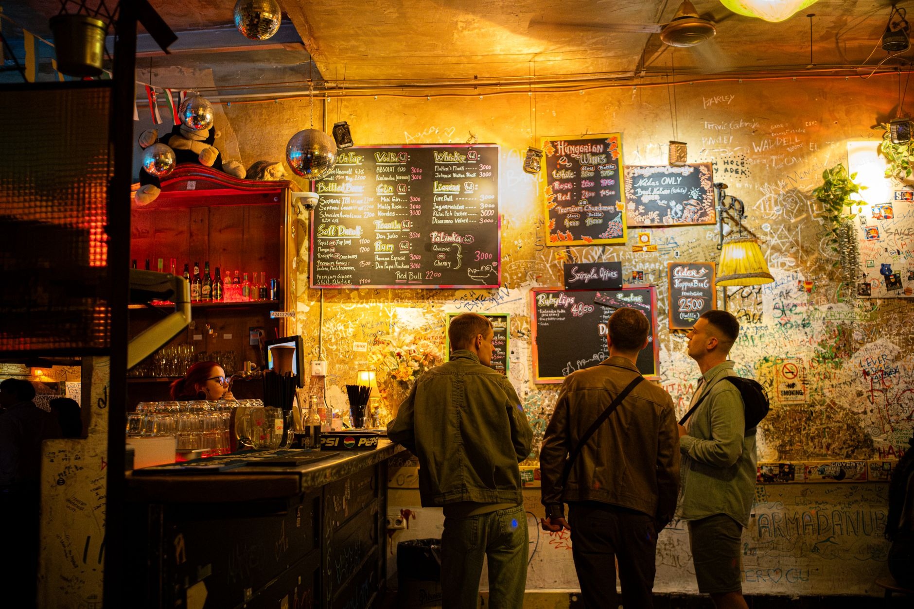 Eclectic open-air courtyard of Szimpla Kert ruin bar in Budapest filled with vintage art hanging plants and warm lighting