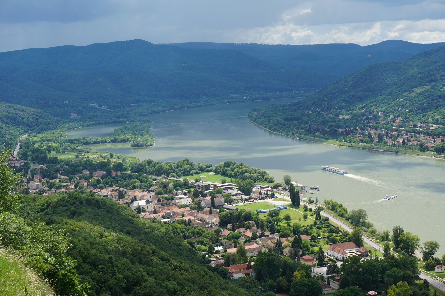 Panoramic view of the Danube Bend river sweeping through forested green mountains seen from Visegrád Castle