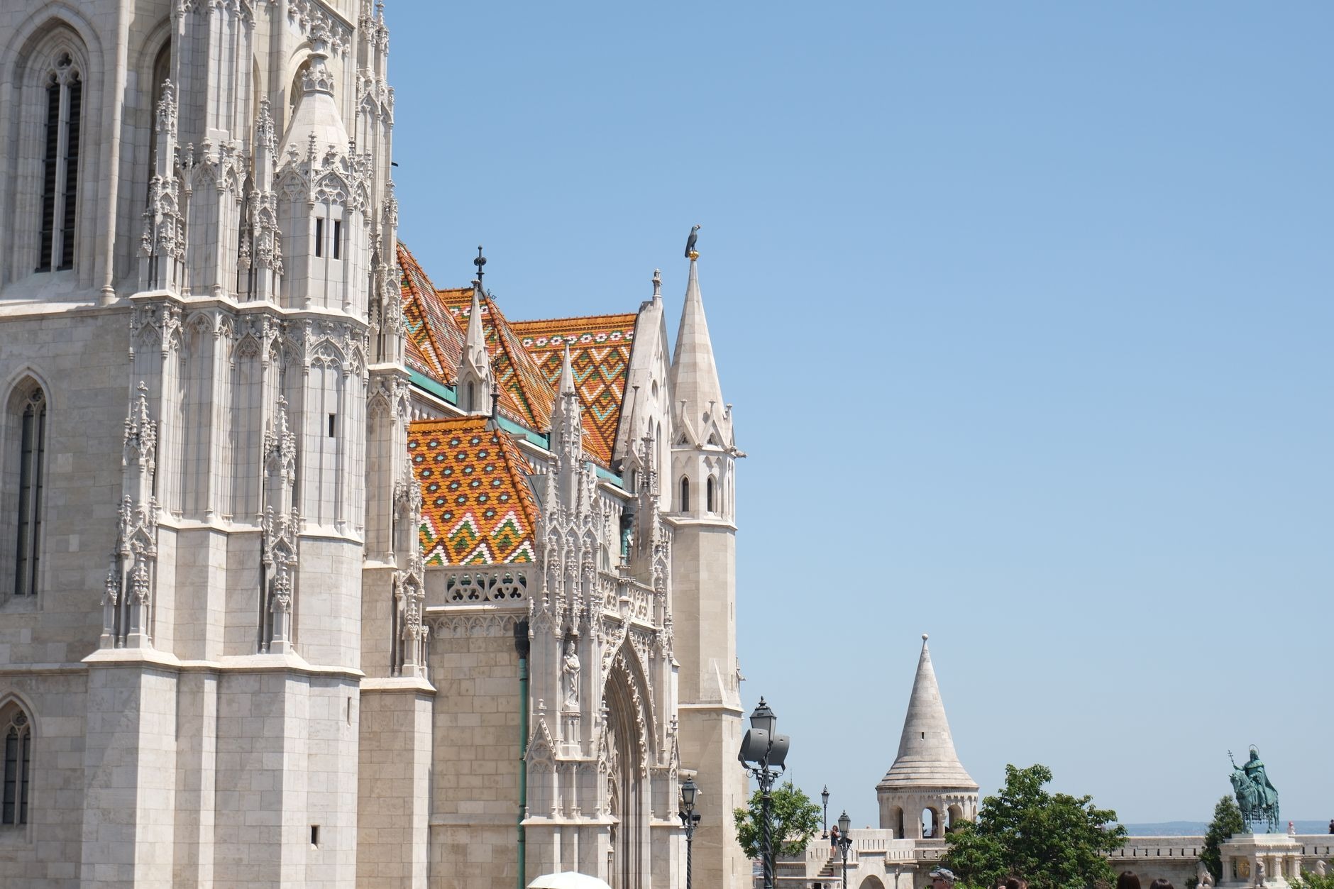 White neo-Romanesque stone turrets of Fisherman's Bastion framing Matthias Church with its colorful diamond-tiled roof in Budapest