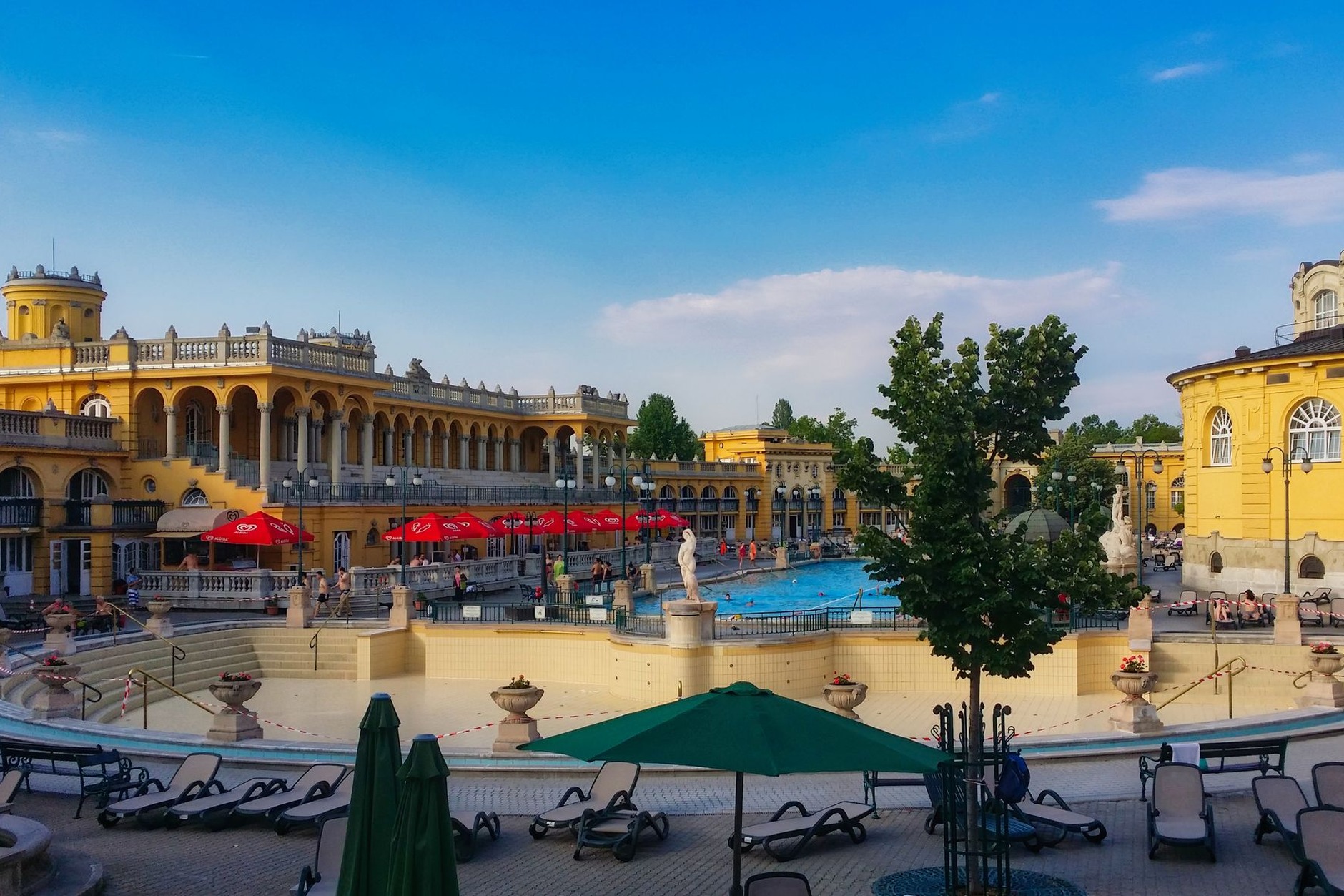 Vast outdoor heated mineral pools and neo-Baroque yellow palace facades of Széchenyi Thermal Baths in Budapest