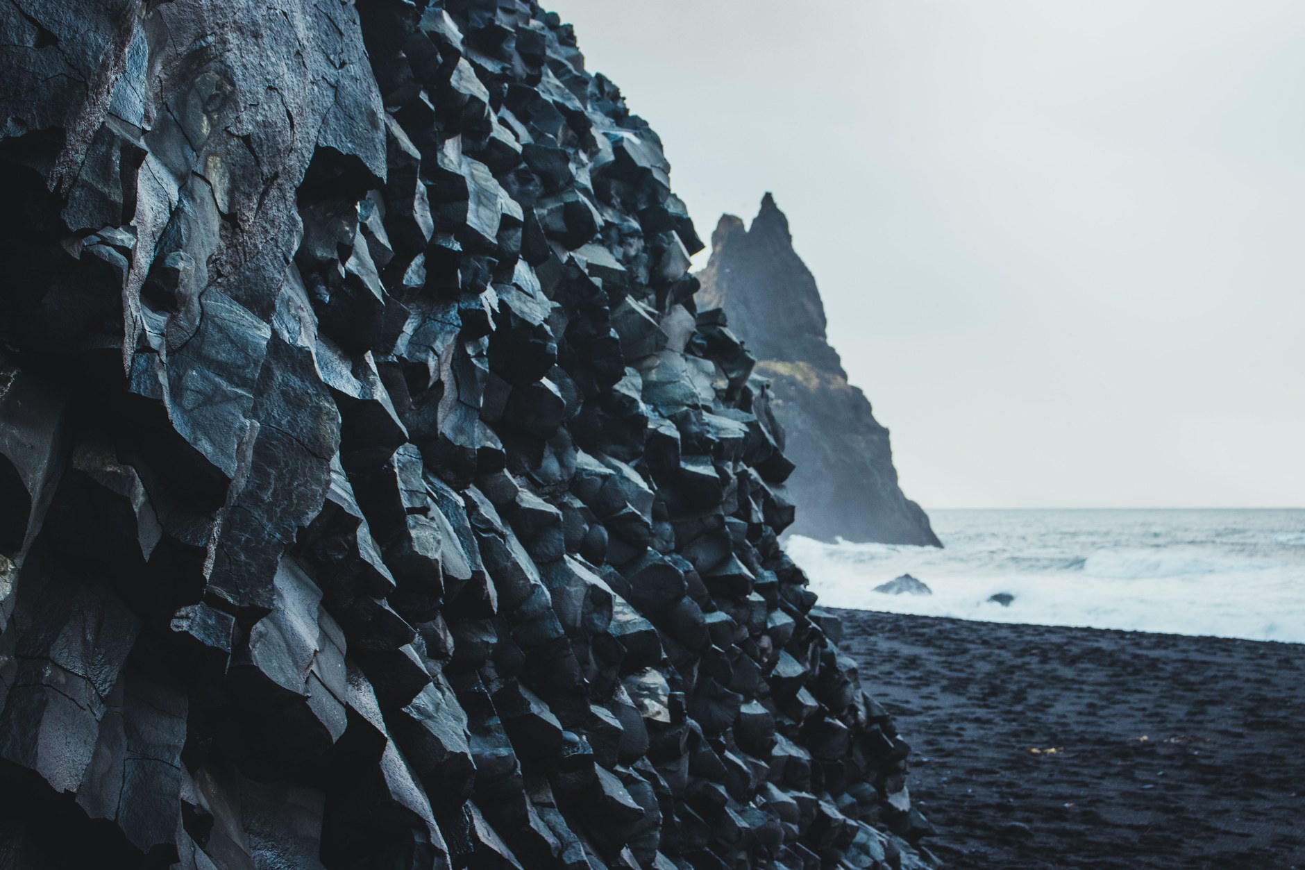 Basalt geometric sea columns and crashing North Atlantic waves at Reynisfjara black sand beach