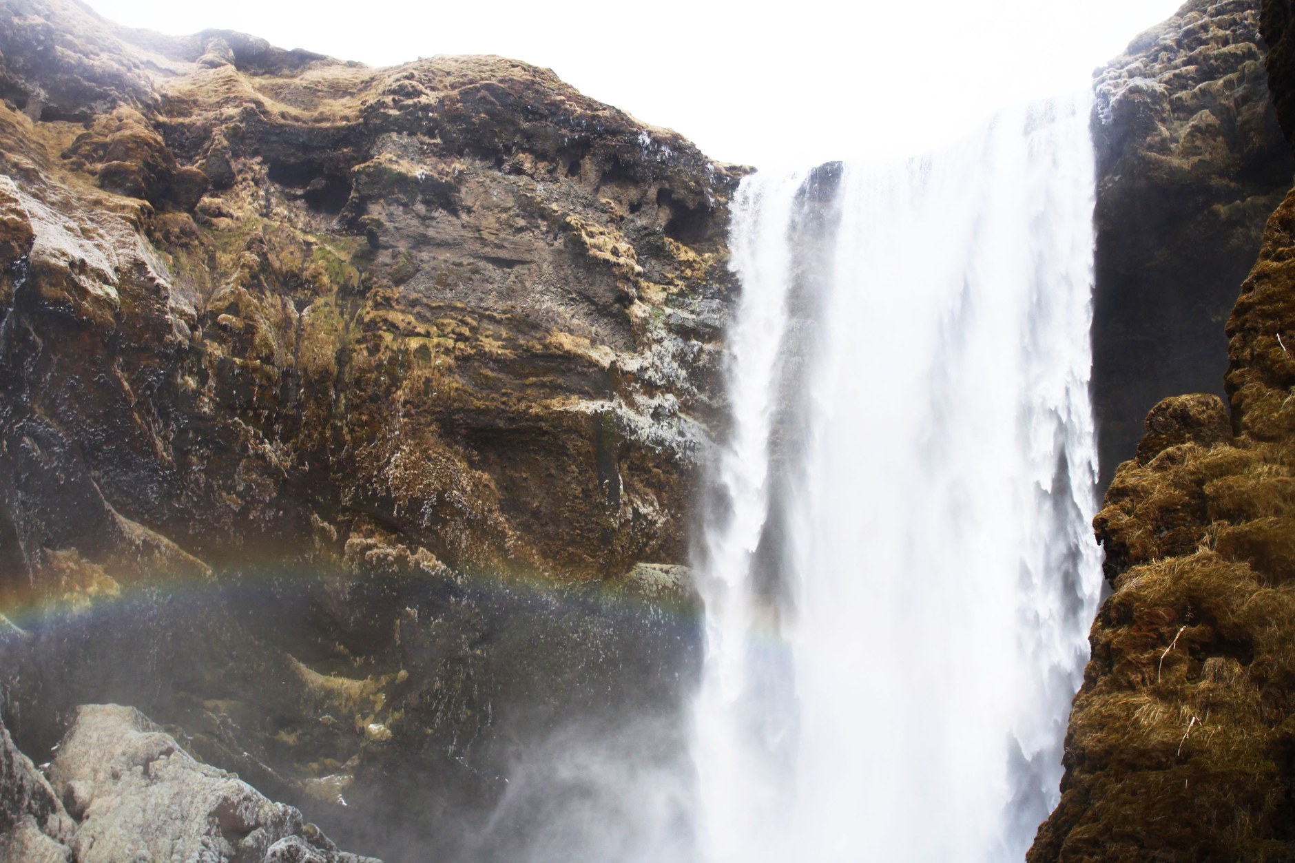 Skógafoss waterfall plunging sixty metres over coastal cliffs with a vivid rainbow