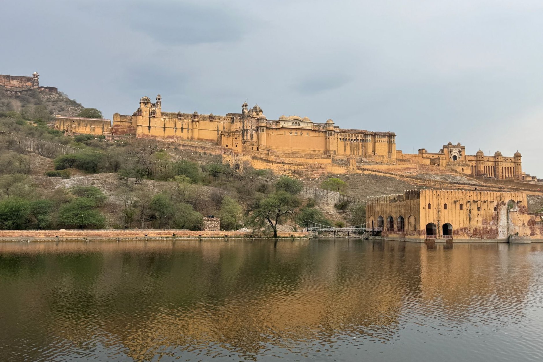 Massive yellow sandstone walls and ramparts of Amber Fort rising above Maota Lake in Jaipur