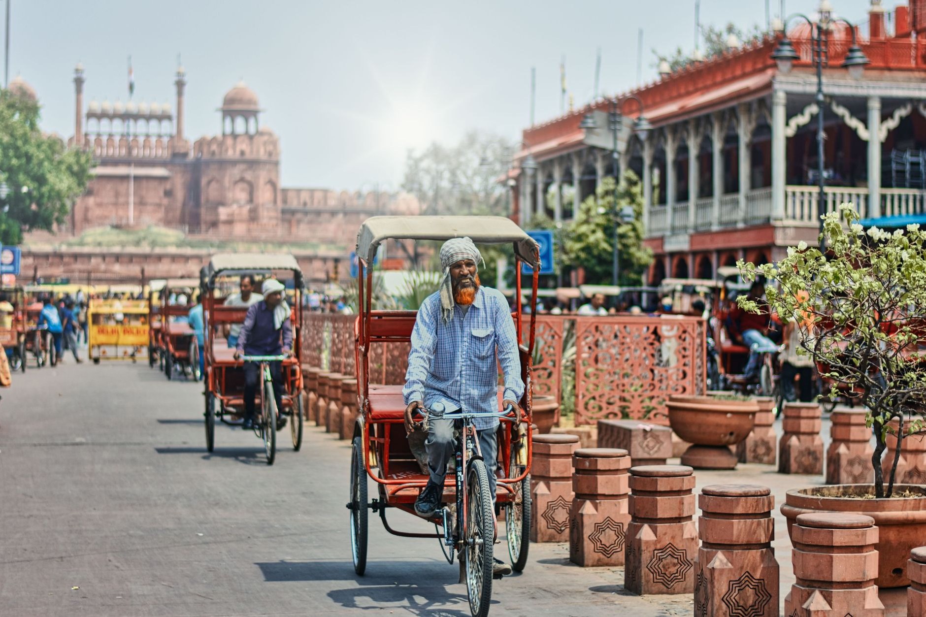 Bustling market street in Old Delhi with cycle rickshaws, pedestrians, and colorful spice stalls