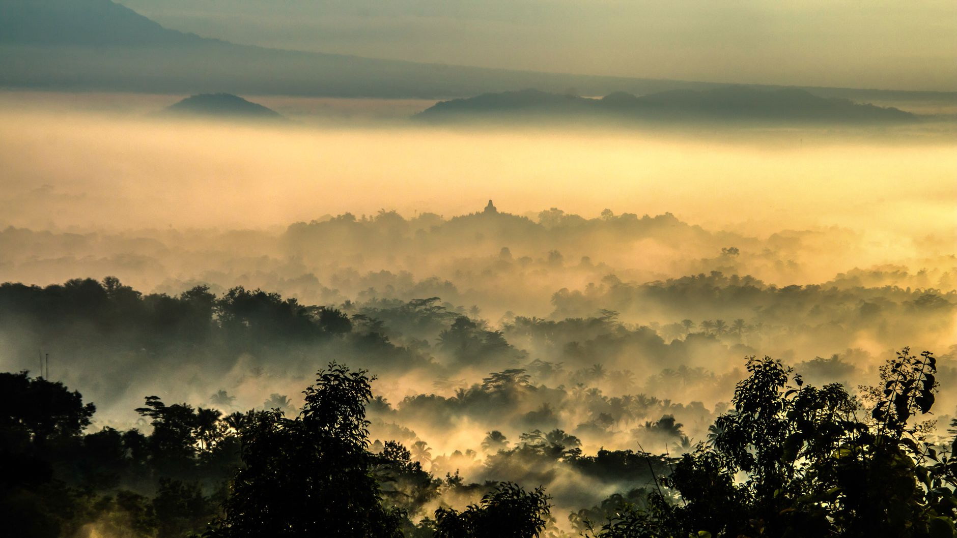 Ancient stupas of Borobudur temple against the morning mist