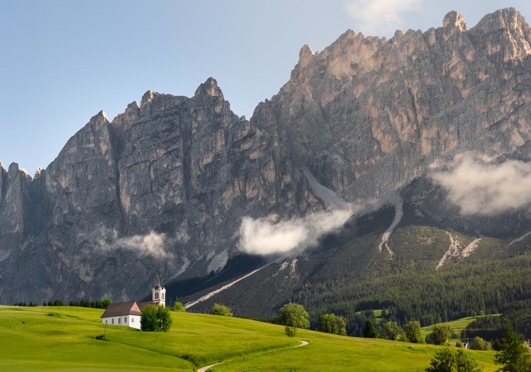 A small church beneath rocky Dolomite peaks