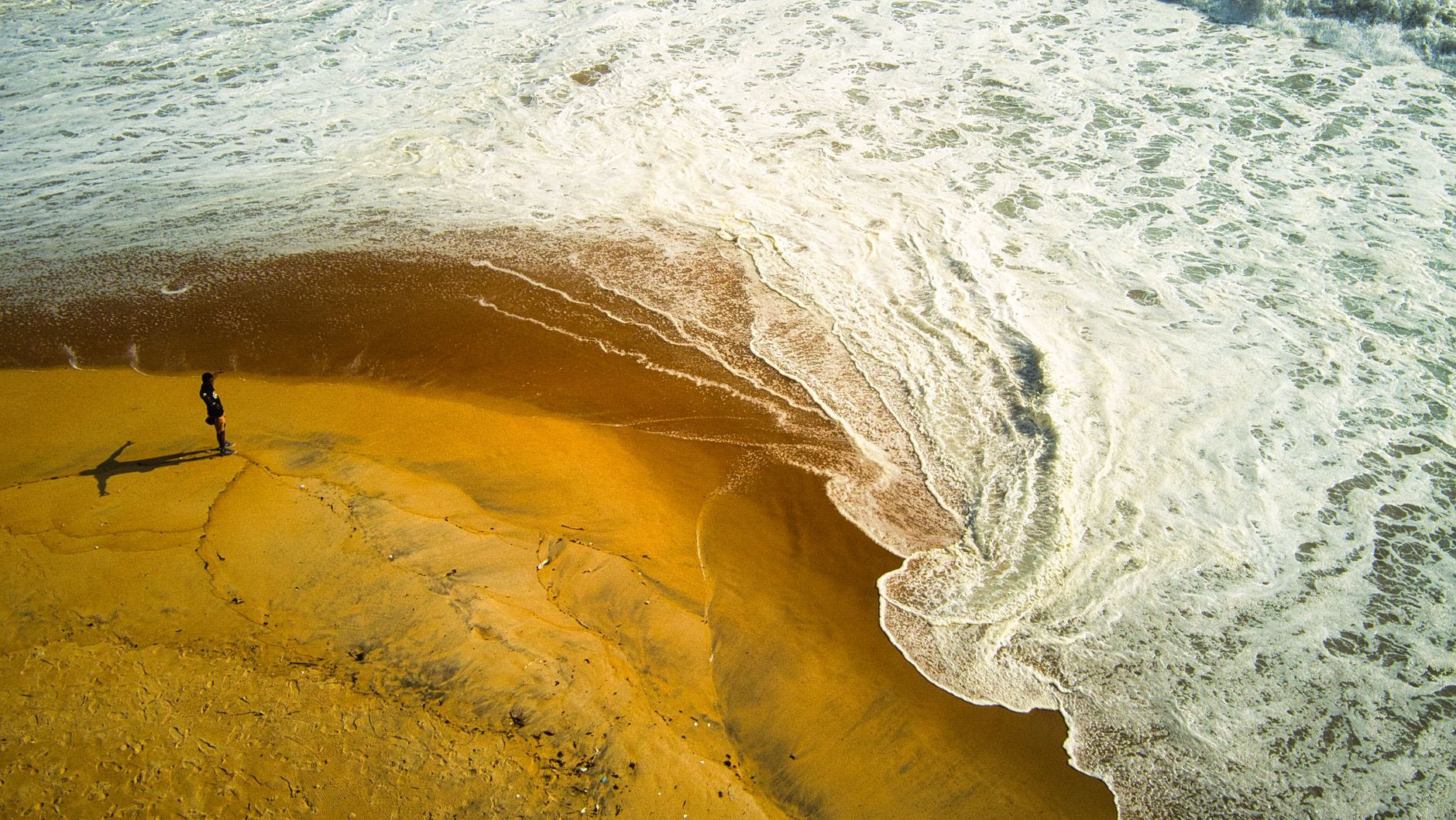 Ocean surf breaking along the wide sandy expanse of Azuretti Beach near Grand-Bassam