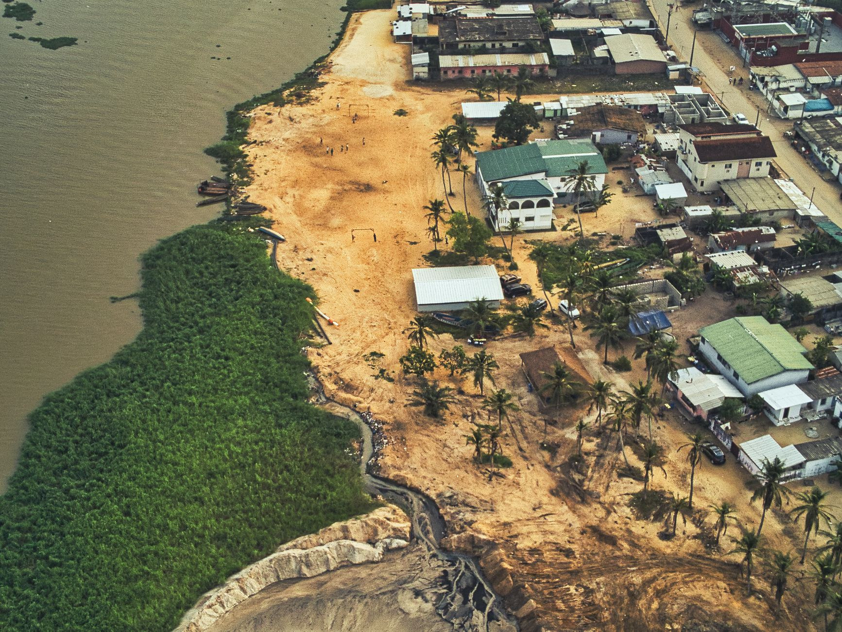 Aerial view of the coastal residential shoreline and palm groves of Grand-Bassam beside the Atlantic Ocean