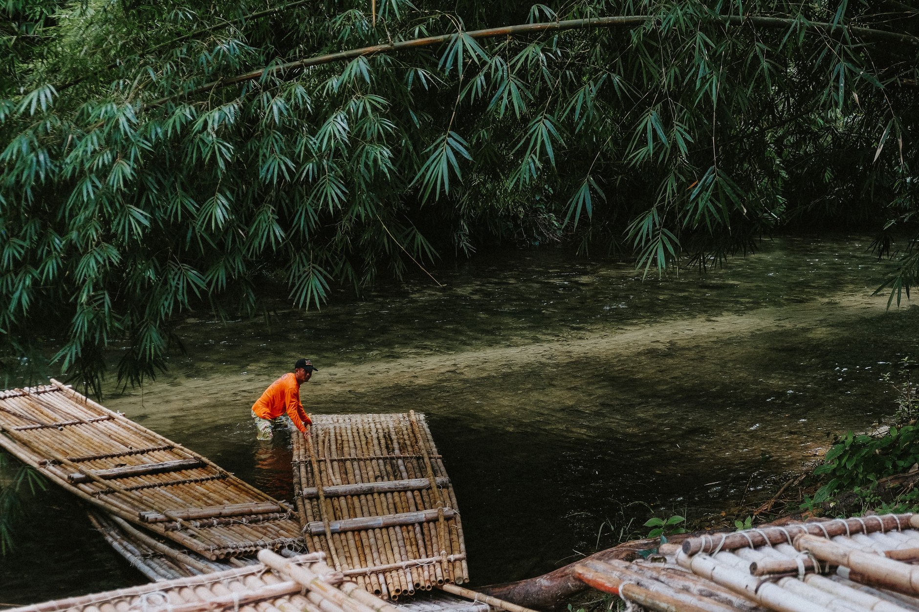 A long handcrafted bamboo raft carrying travelers down the gentle tropical waters of the Rio Grande river in Portland Jamaica