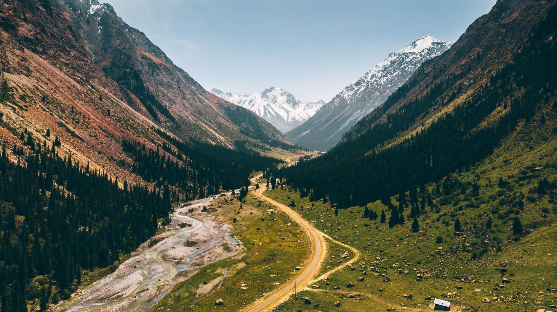 Towering red sandstone cliffs of Jeti-Oguz (Seven Bulls) rising dramatically above alpine pine forests in Kyrgyzstan