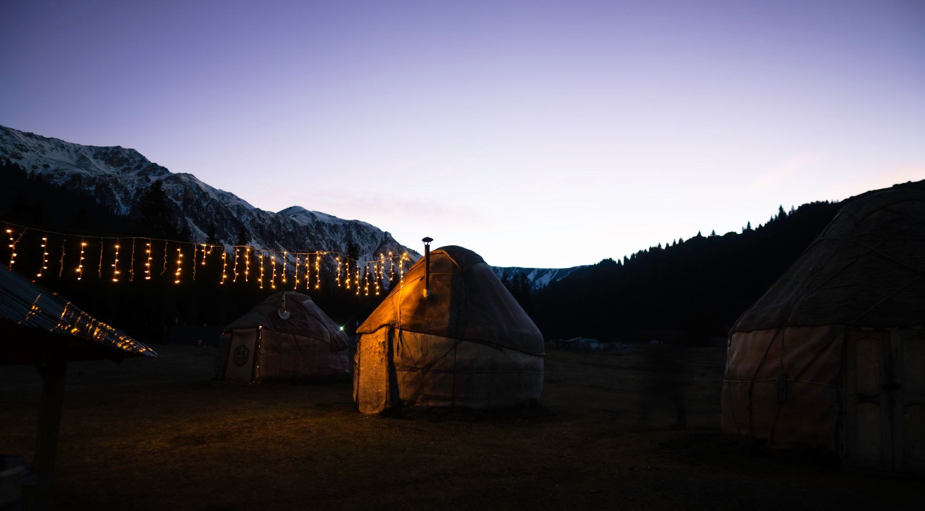 Close-up of a traditional Kyrgyz felt yurt showing the circular wooden tunduk roof crown and embroidered felt blankets