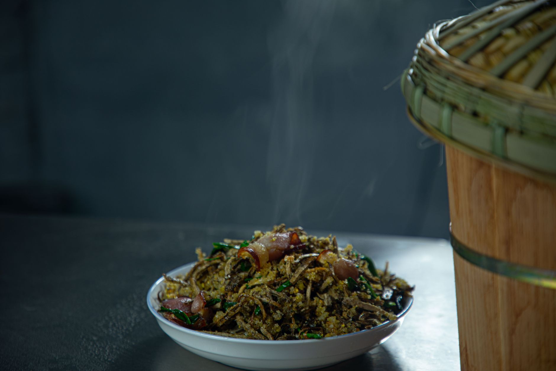 Traditional Lao meal featuring spicy chicken larb herb salad, steamed sticky rice in a woven bamboo basket, and fresh vegetables