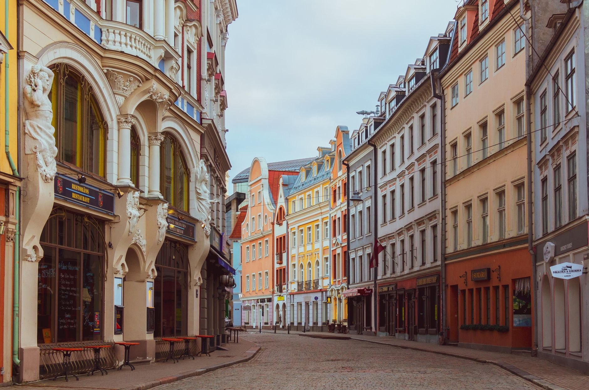 Pedestrian cobblestone street flanked by colorful restored medieval merchant houses in Old Riga