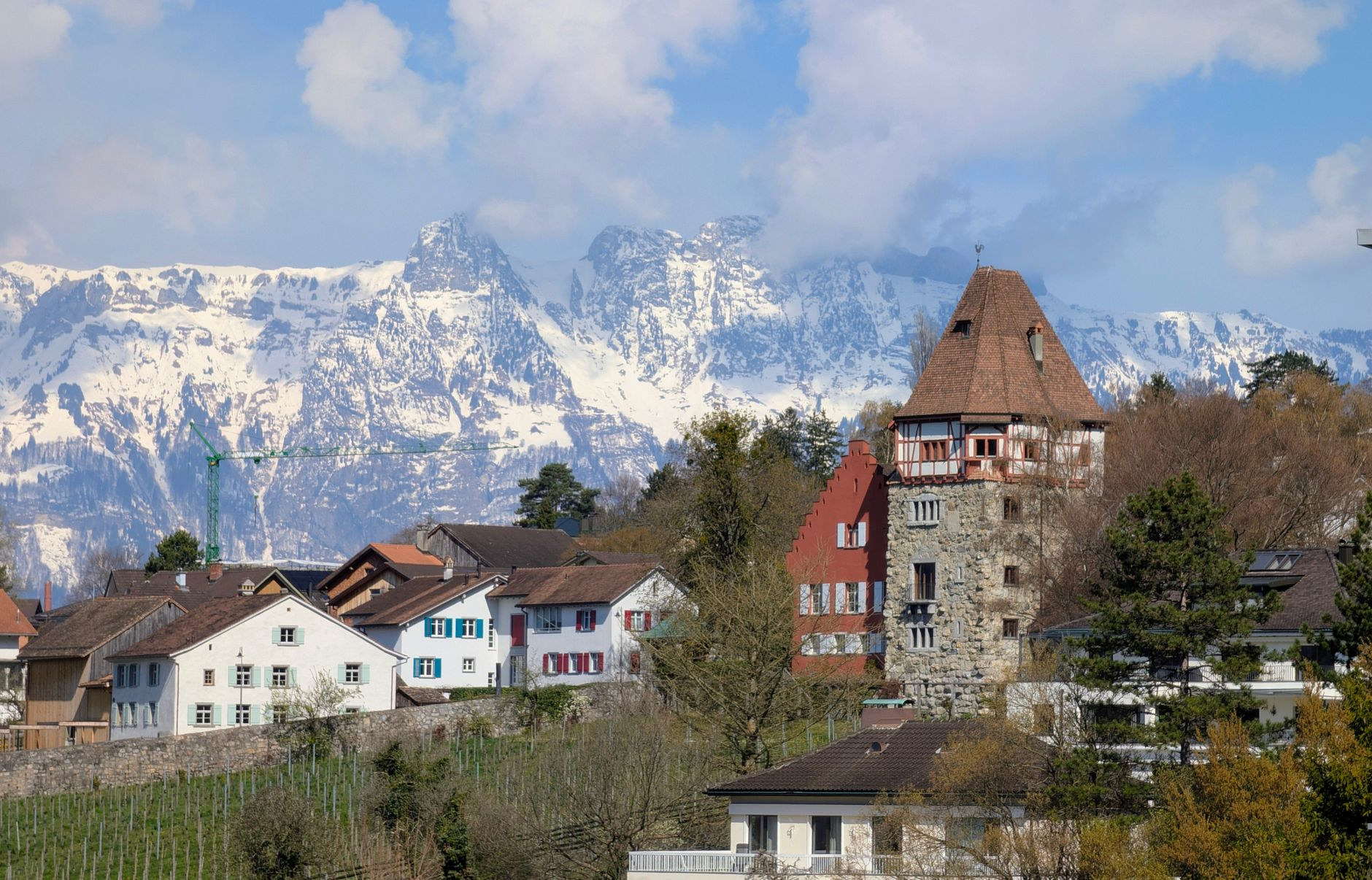 Charming alpine chalet homes and church spire set beneath rugged snow-streaked mountain crests