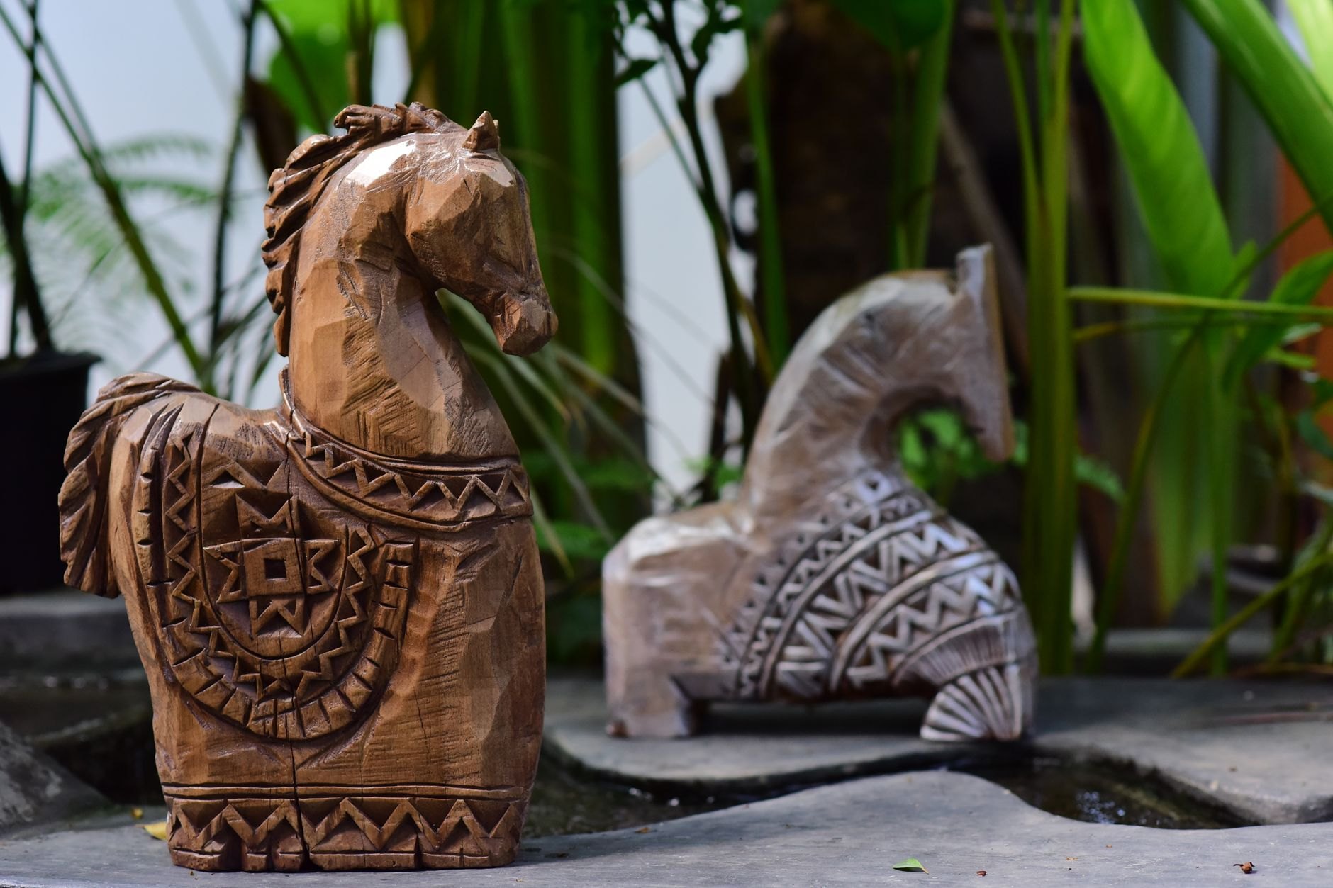 Intricately carved oak folk sculpture depicting mythical folklore figures along a shaded pine forest trail in Juodkrantė