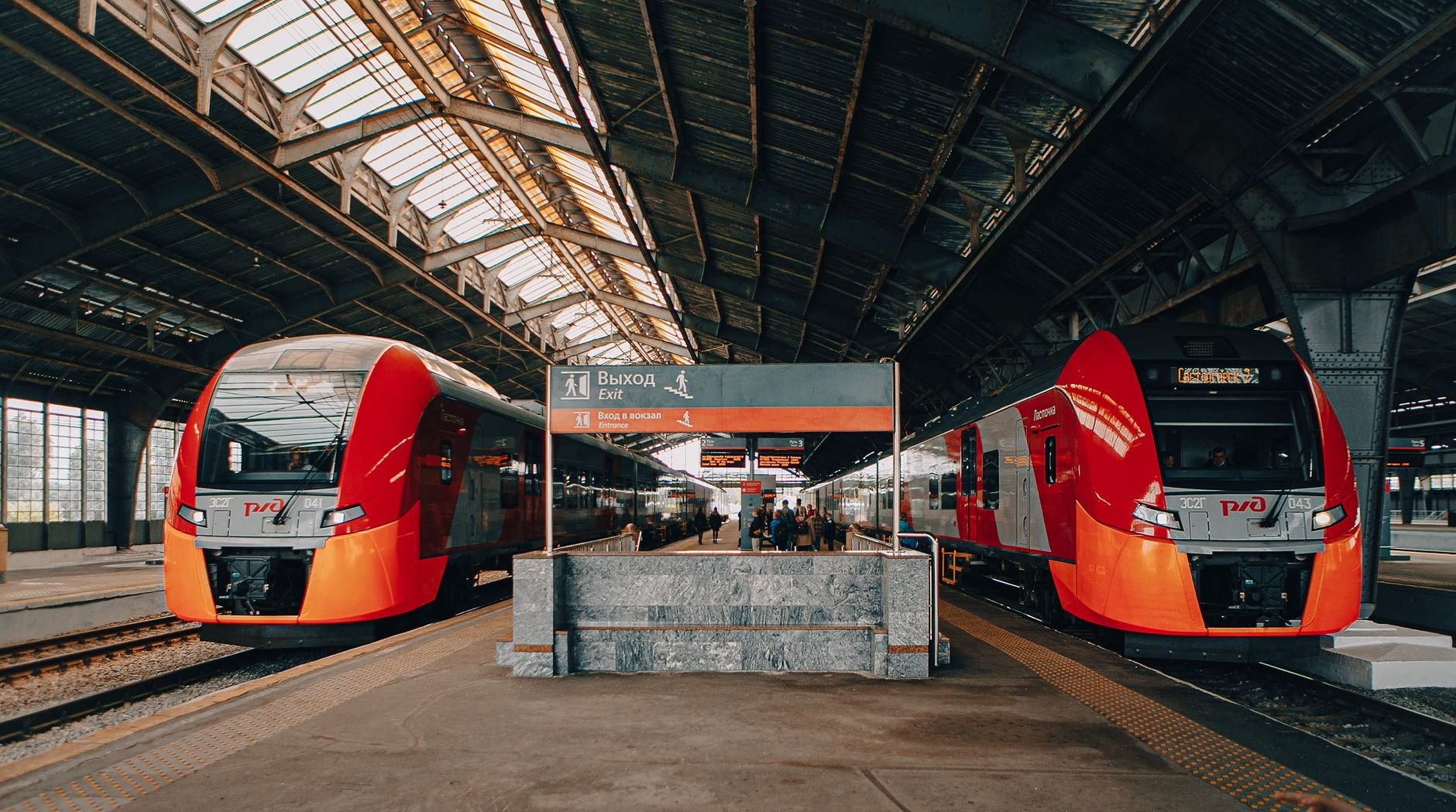 Sleek modern red passenger train resting at a railway platform before departing on an intercity route