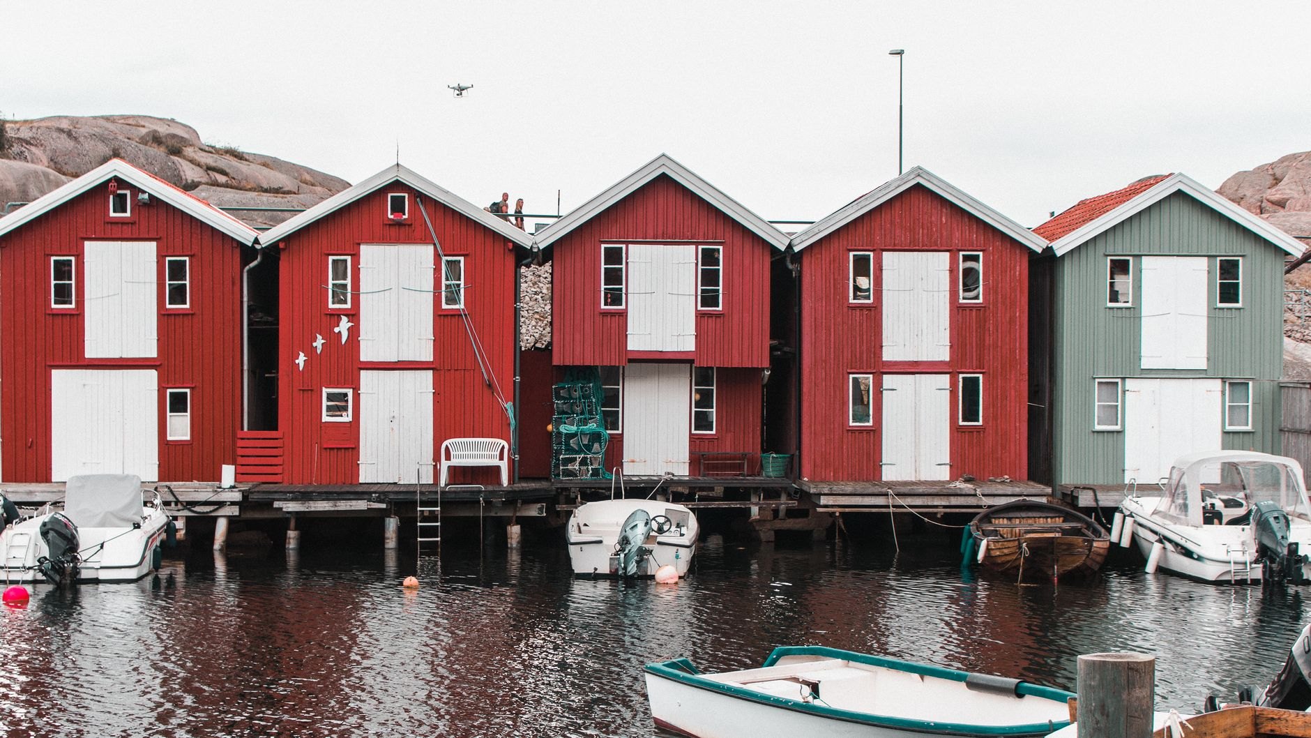 Traditional dark brown and blue-trimmed wooden fisherman house with ornate carved gables and flower garden in Nida