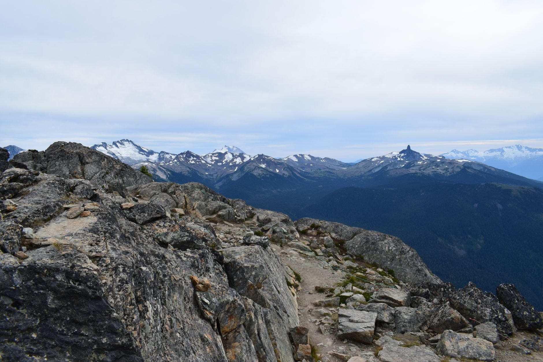 High mountain hiking trail along a rocky limestone ridge overlooking panoramic blue lake waters far below