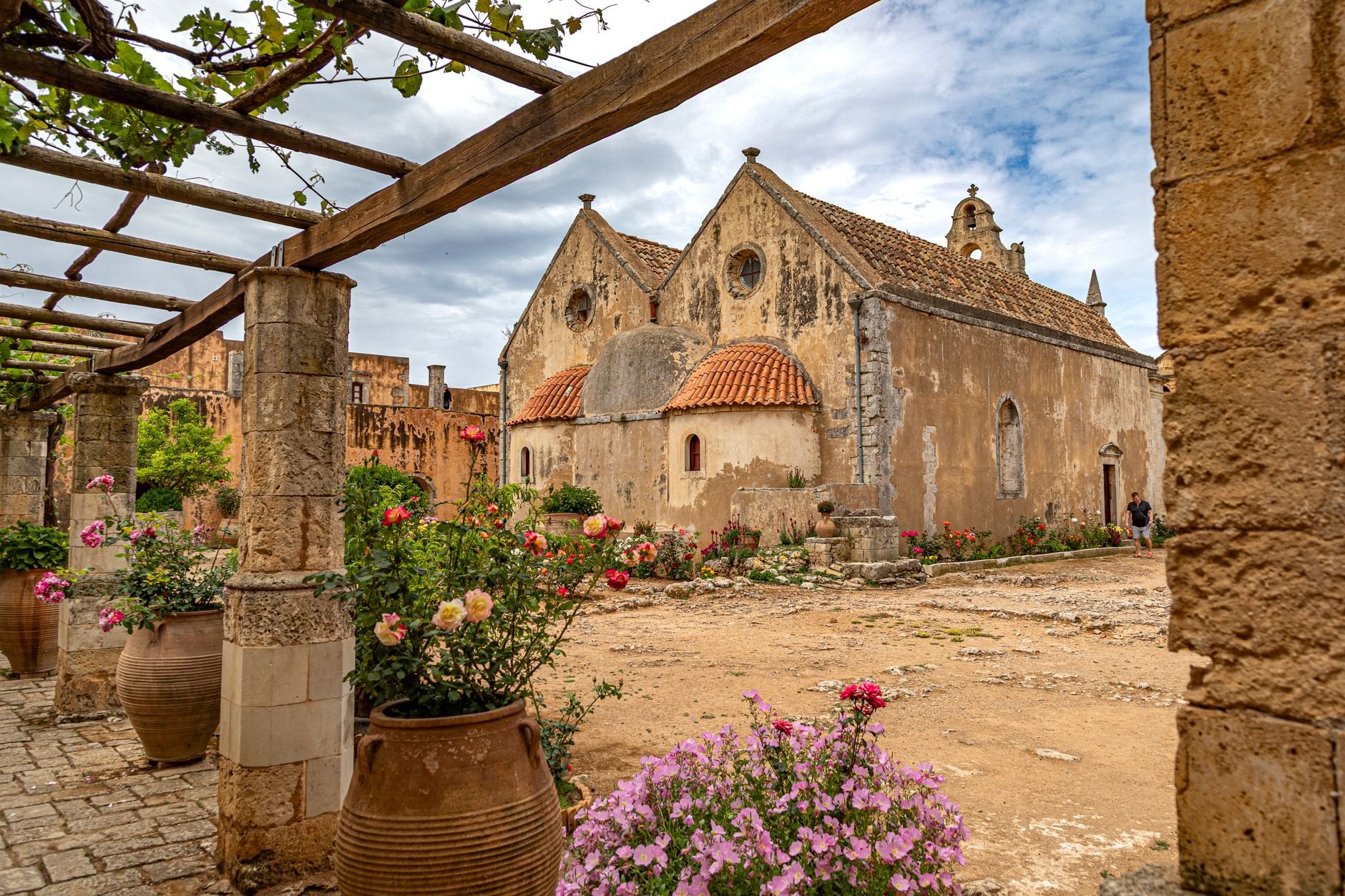Historic stone monastery church surrounded by peaceful rose gardens and free-roaming peacocks at Saint Naum
