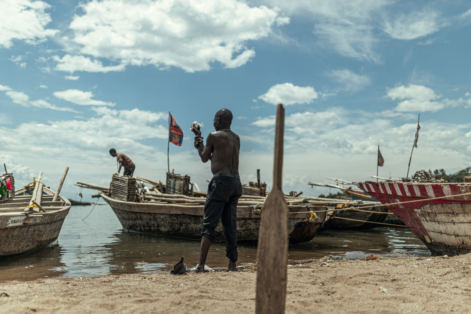 Local fishermen preparing handcrafted wooden dugout canoes along a tranquil sandy lakeside beach in the early morning
