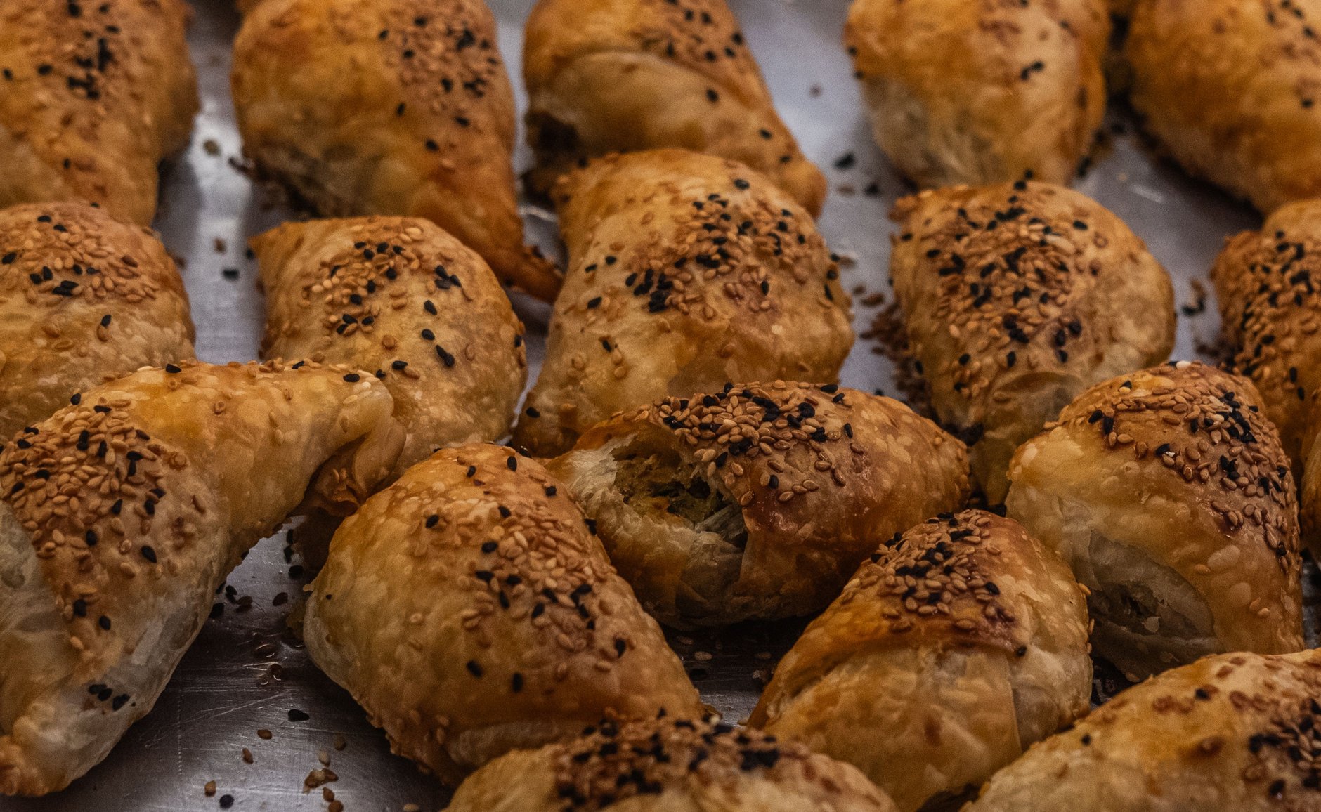 Golden flaky diamond-shaped freshly baked pastizzi filled with warm ricotta cheese on a traditional bakery plate