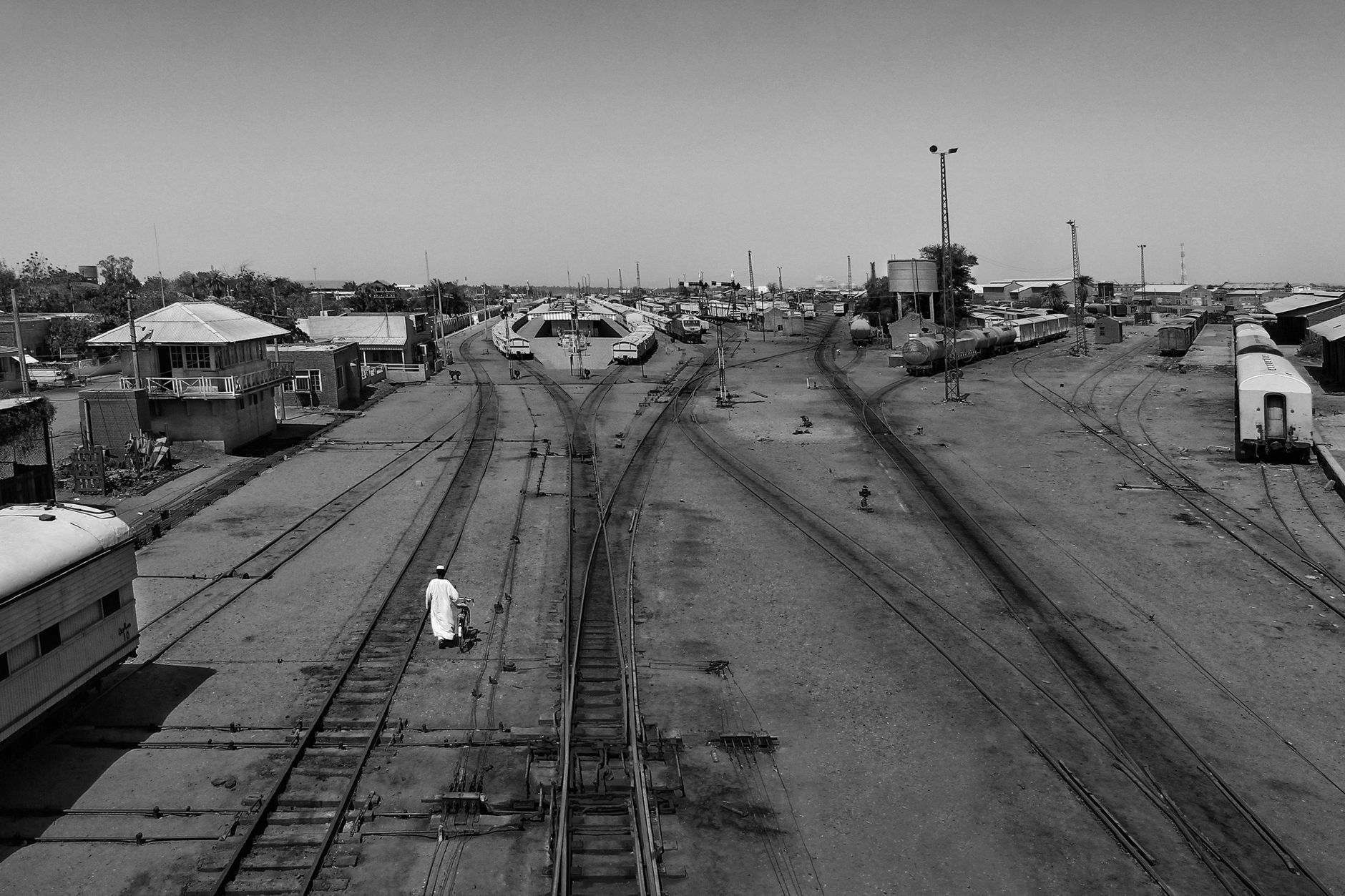 Overhead perspective of desert railway tracks and freight carriages crossing the open Saharan expanse