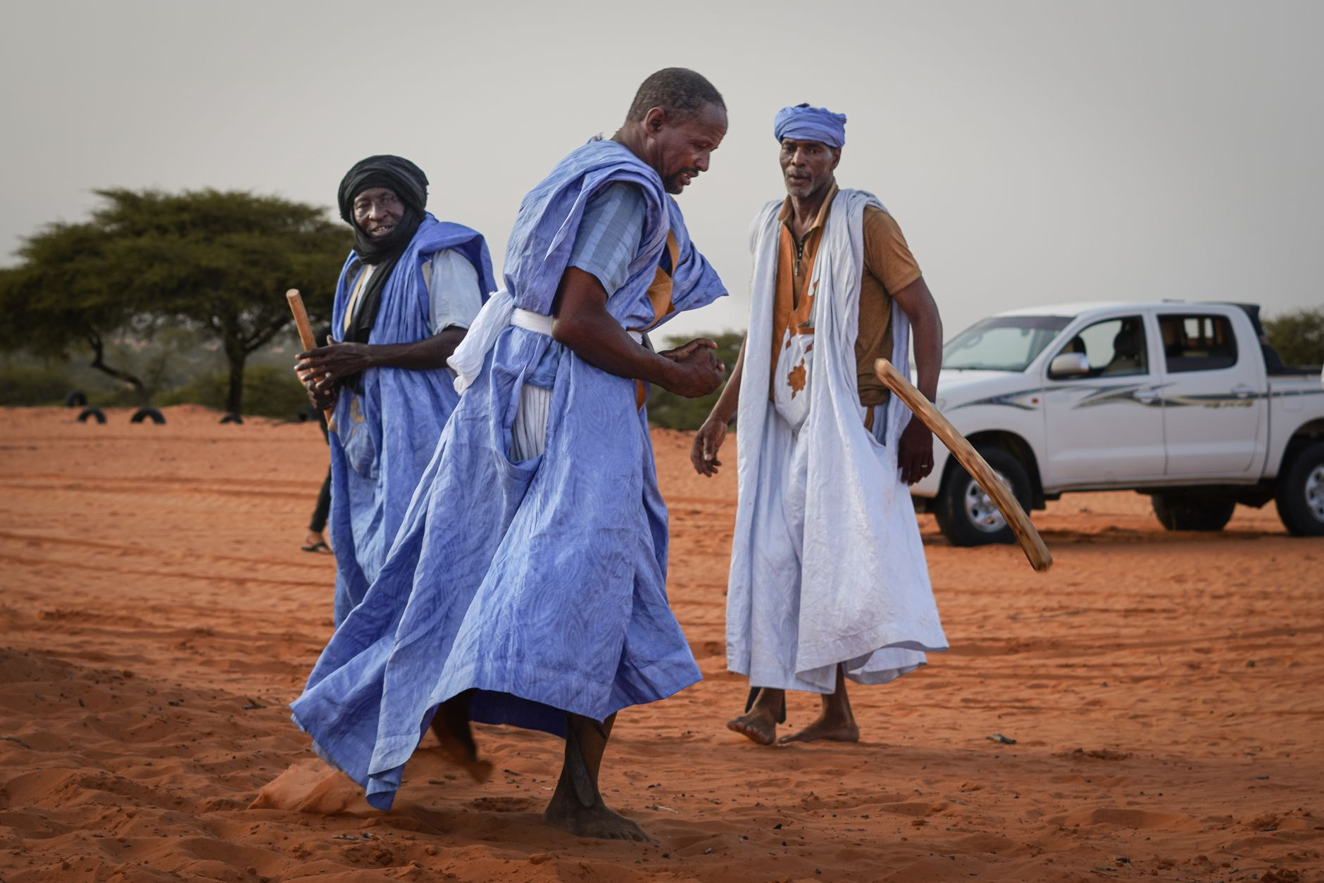 Mauritanian men in traditional indigo boubou robes participating in a Saharan cultural gathering