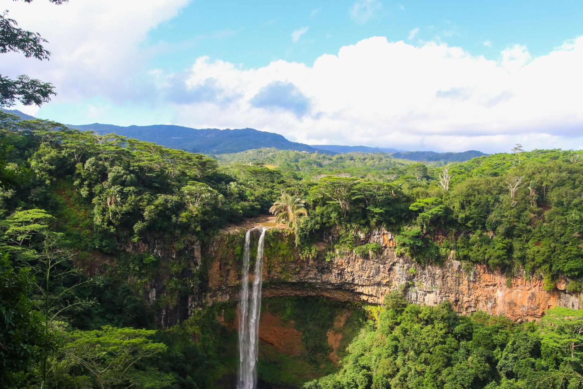 Chamarel Waterfall plunging 100 meters into a lush green volcanic canyon amphitheater surrounded by tropical rainforest
