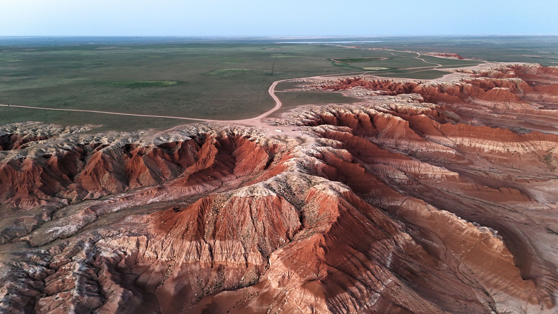 Dramatic eroded red sandstone buttes and ravines of Bayanzag glowing fiery orange in the late afternoon Gobi sun