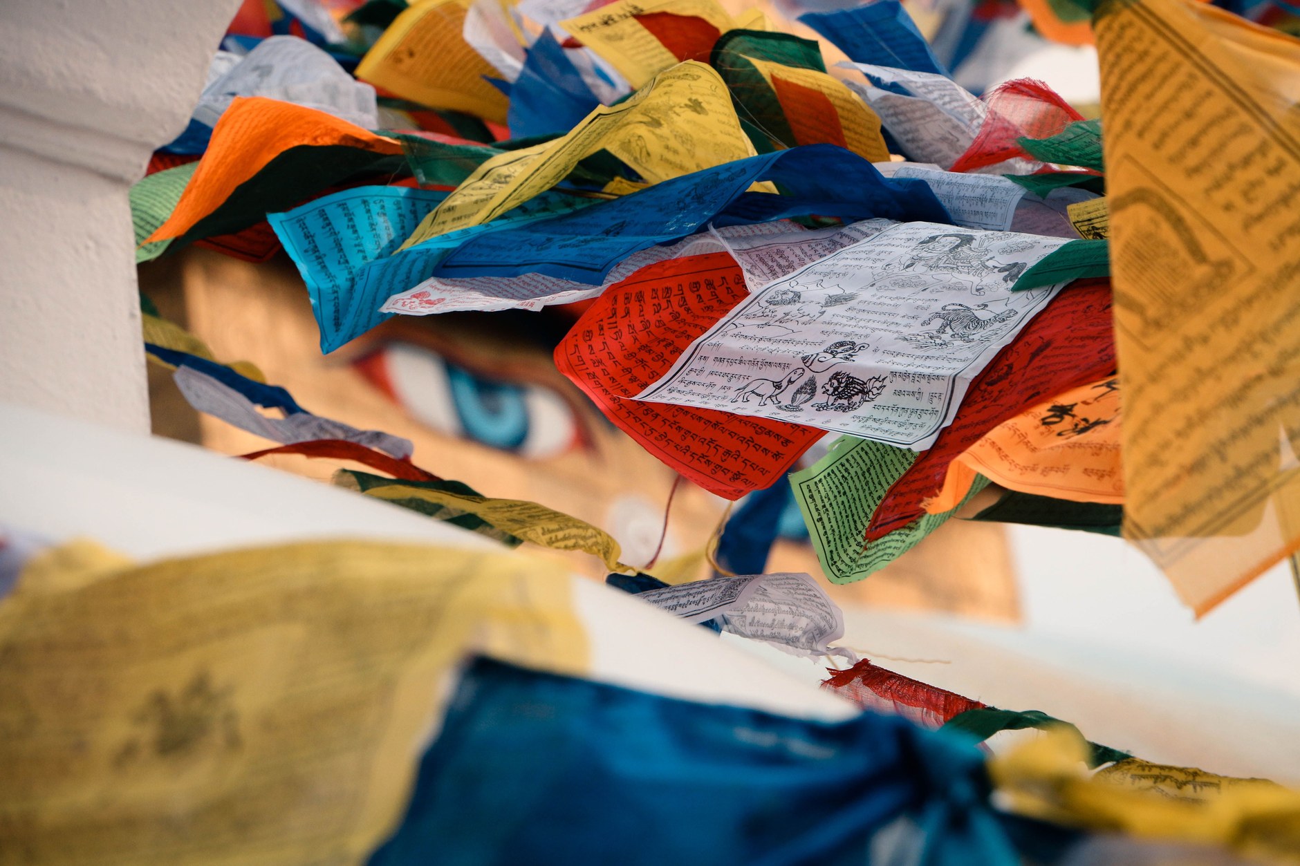 The giant white dome and painted eyes of Boudhanath Stupa draped in colorful prayer flags in Kathmandu