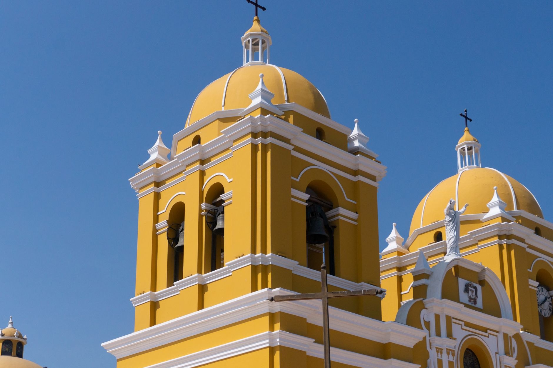 Warm yellow facade and baroque bell tower of Iglesia de la Merced overlooking tile-roofed colonial Granada