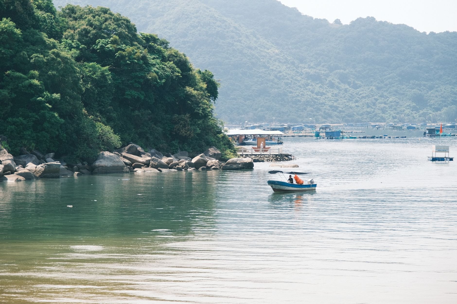 Small wooden tour boat navigating calm channel waters between lush tropical volcanic islets in Lake Nicaragua