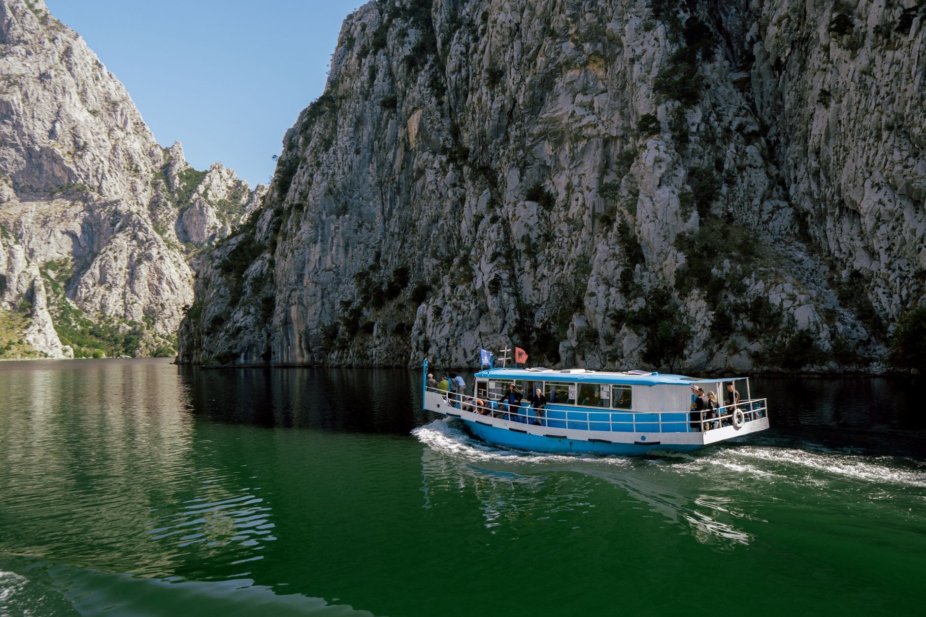 Sturdy passenger ferry cruising across open lake water with the silhouette of volcanic peaks on the horizon