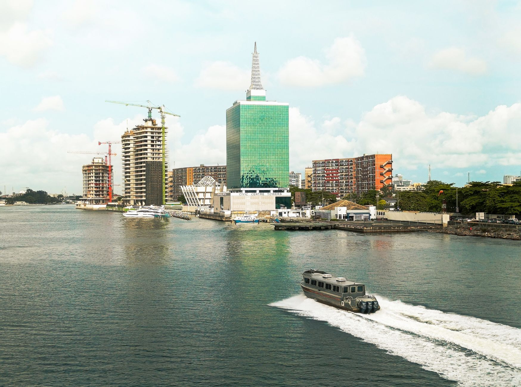 Modern high-rise commercial buildings along the water with motorboats cruising across Lagos Lagoon