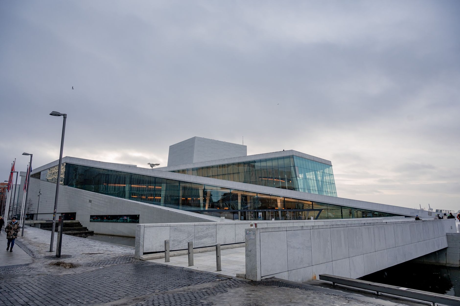 White sloping marble roof of the Oslo Opera House rising from the fjord waters