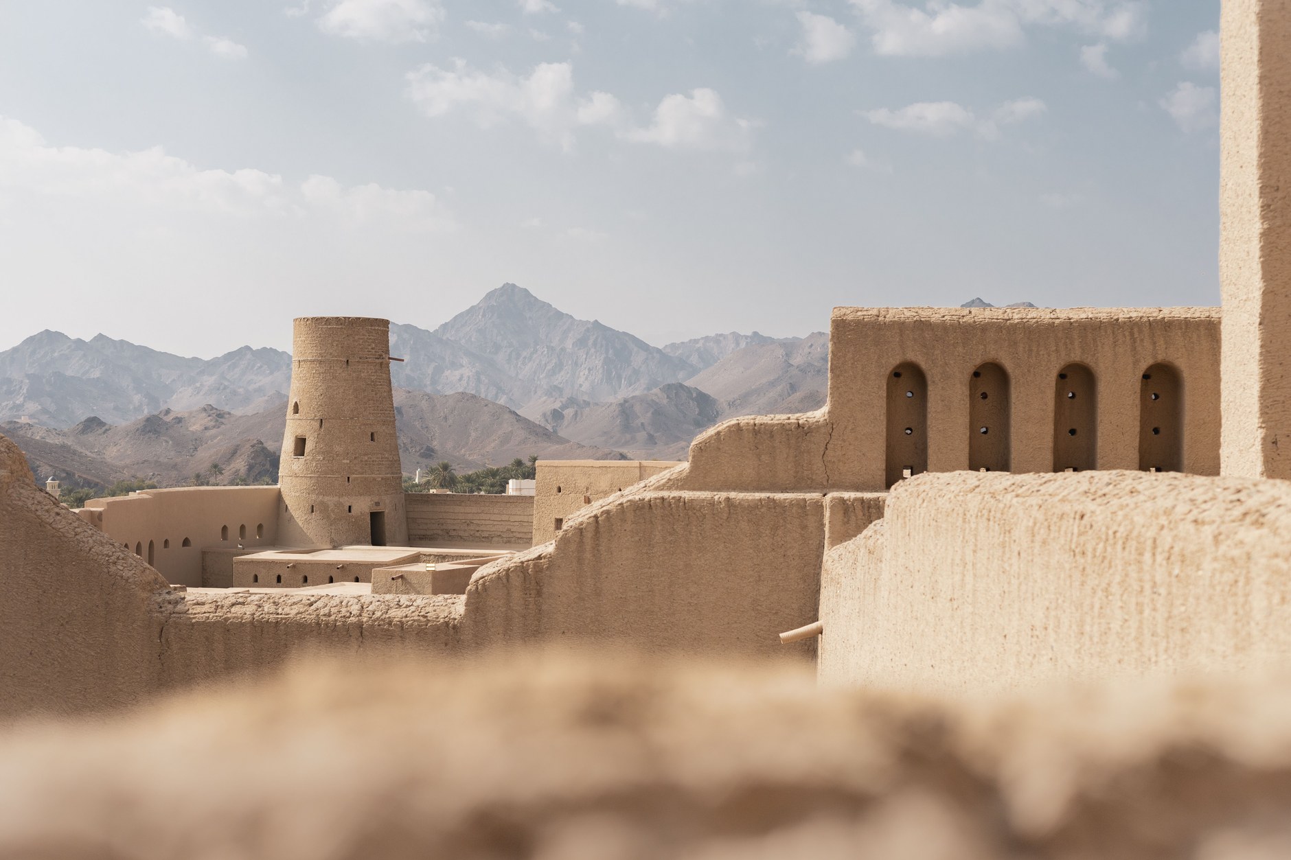 The colossal 17th-century circular cannon tower of Nizwa Fort surrounded by date palm oases