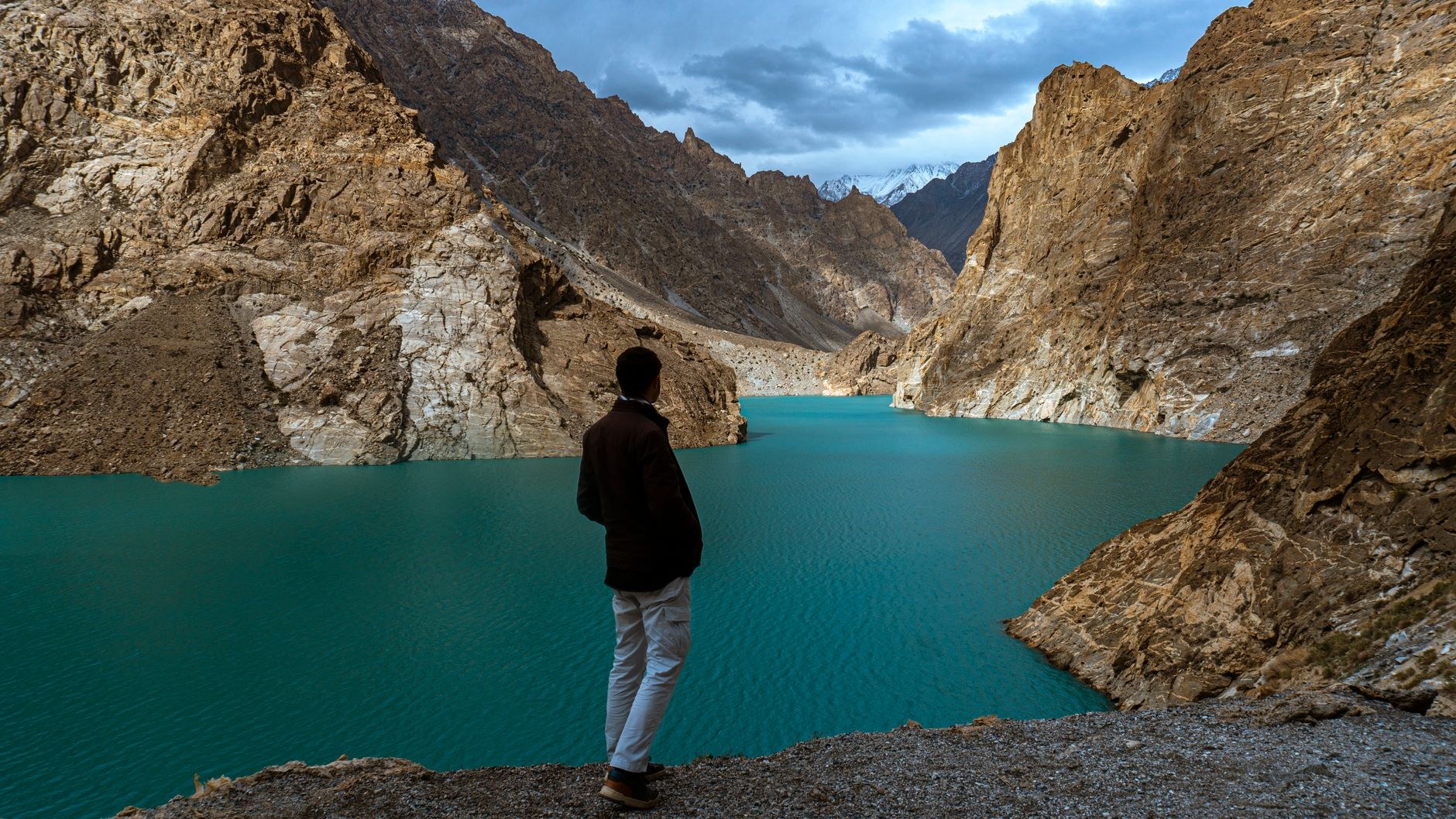 Luminous turquoise waters of Attabad Lake filling a steep rocky canyon between jagged barren peaks in Upper Hunza