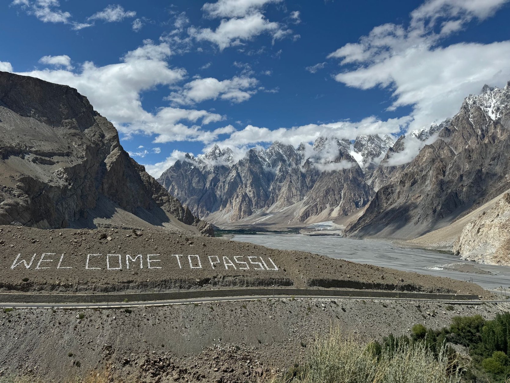 Paved asphalt ribbon of the Karakoram Highway carved through sheer vertical granite canyon cliffs along the Indus River