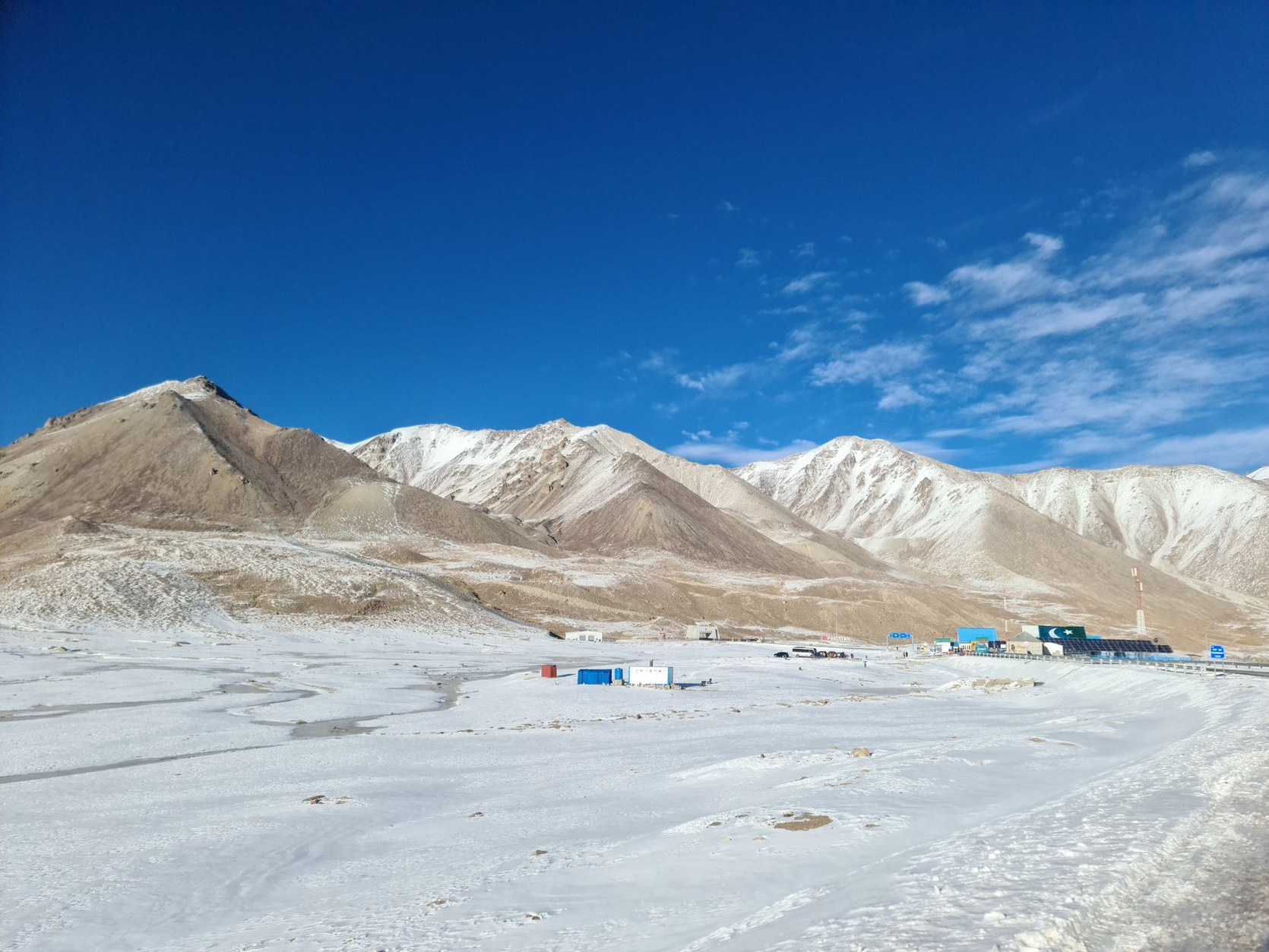 High-altitude paved highway and monumental stone border gate at Khunjerab Pass at 4,693 metres elevation