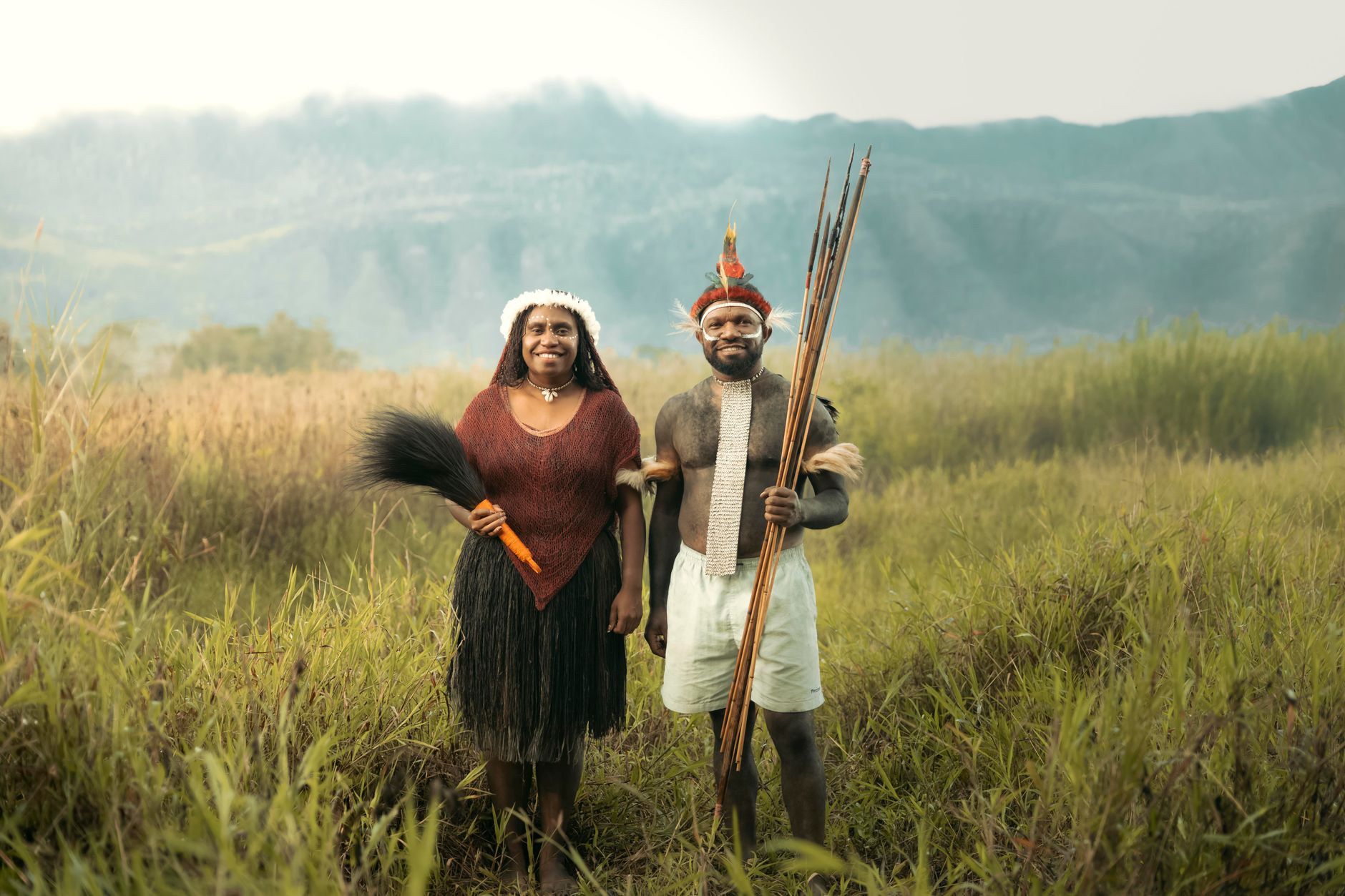 Highlands residents in traditional grass skirts and ceremonial attire standing on a mountain ridge in Papua New Guinea
