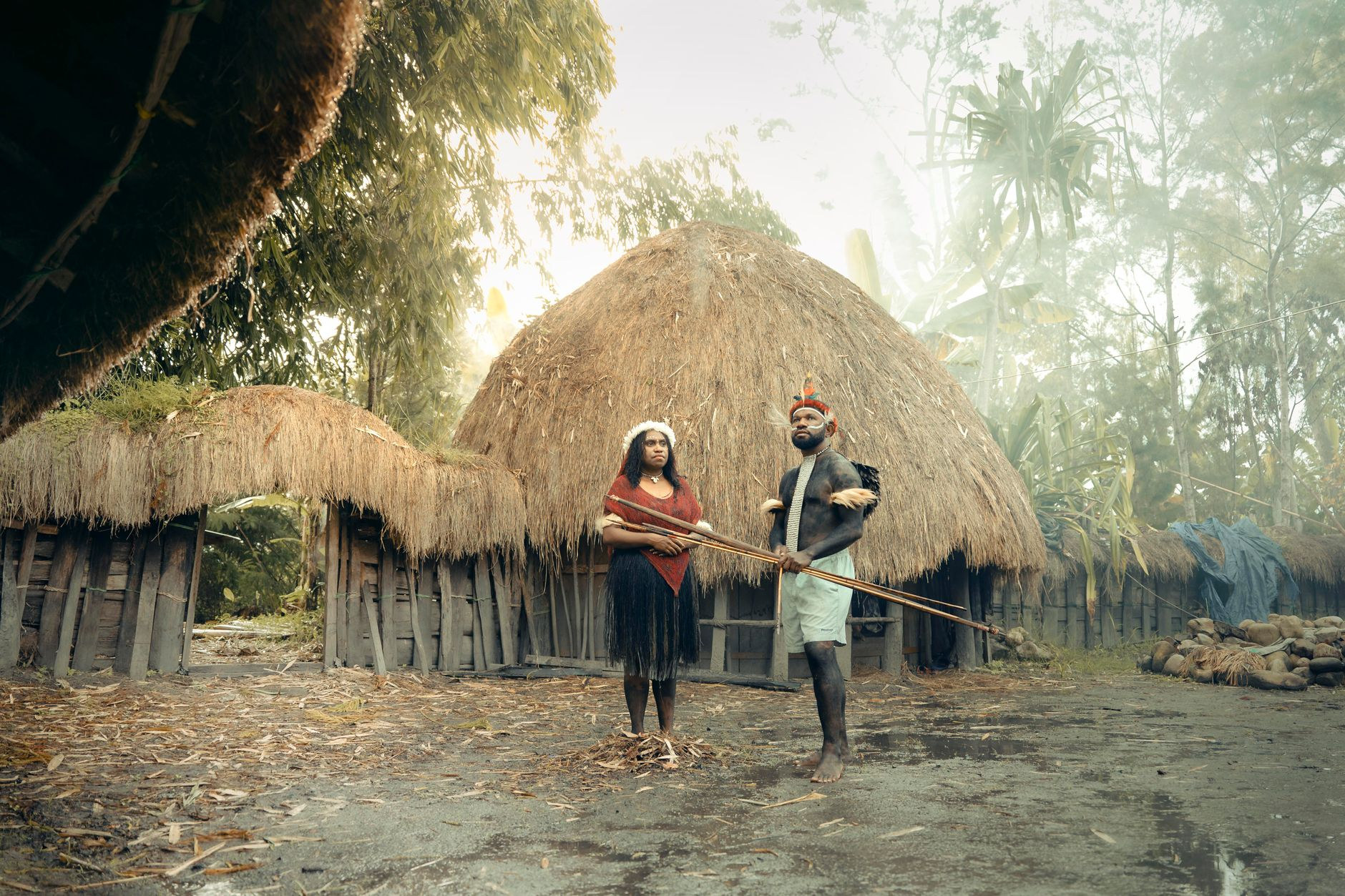 Traditional thatched roundhouse village dwellings and local residents in rural Papua New Guinea