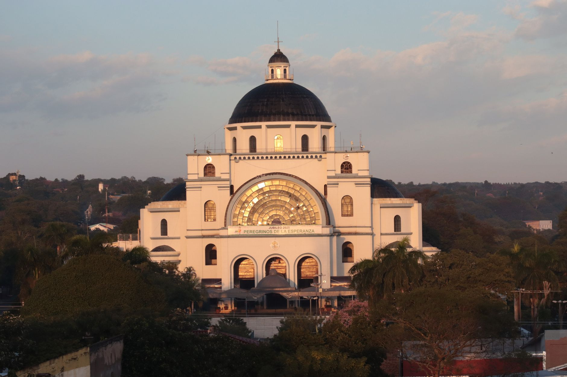 Grand copper-toned dome and monumental facade of the Basilica of Our Lady of the Miracles in Caacupé during sunset