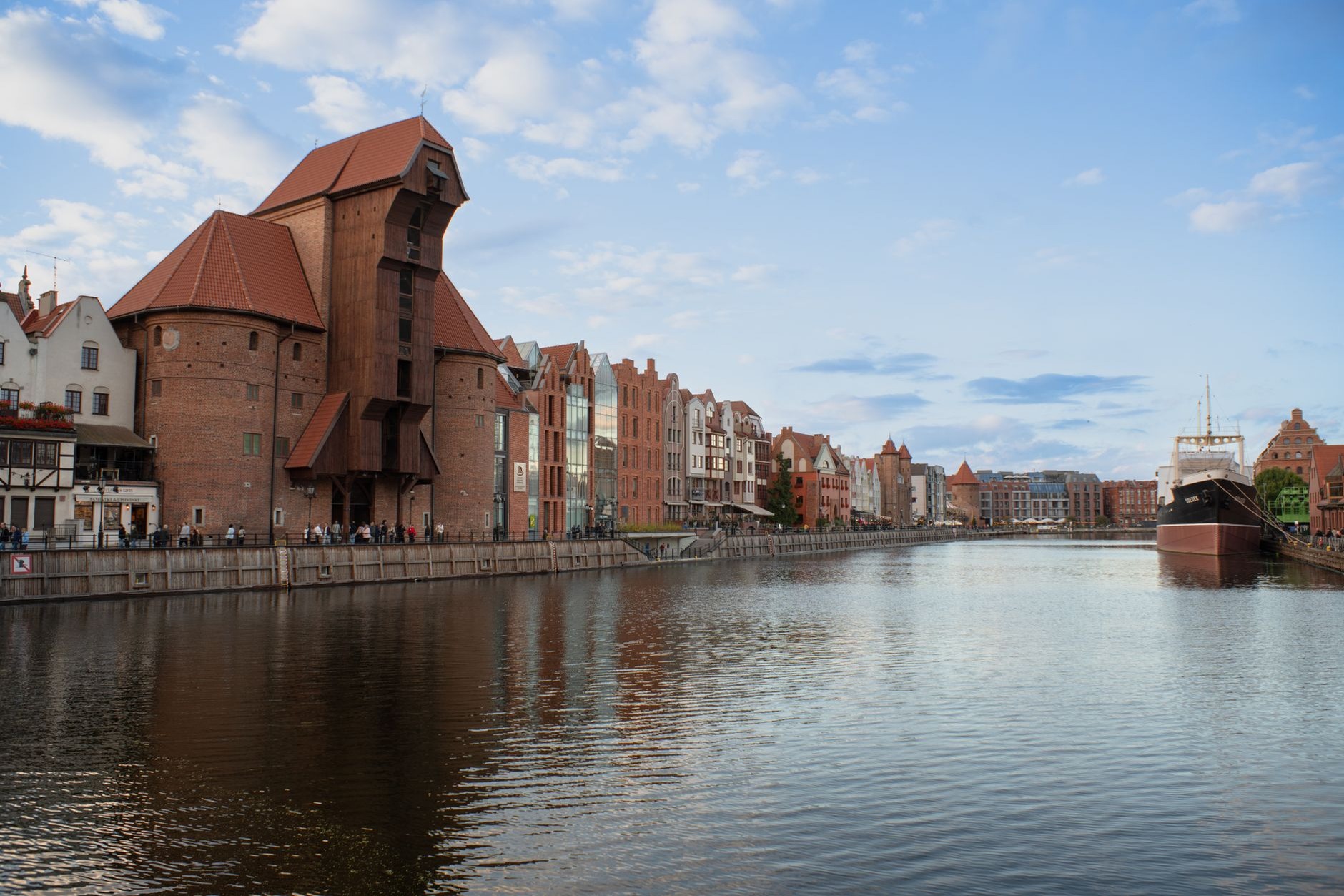 Historic medieval wooden port crane Zuraw and ornate merchant facades along the Motlawa riverfront in Gdansk