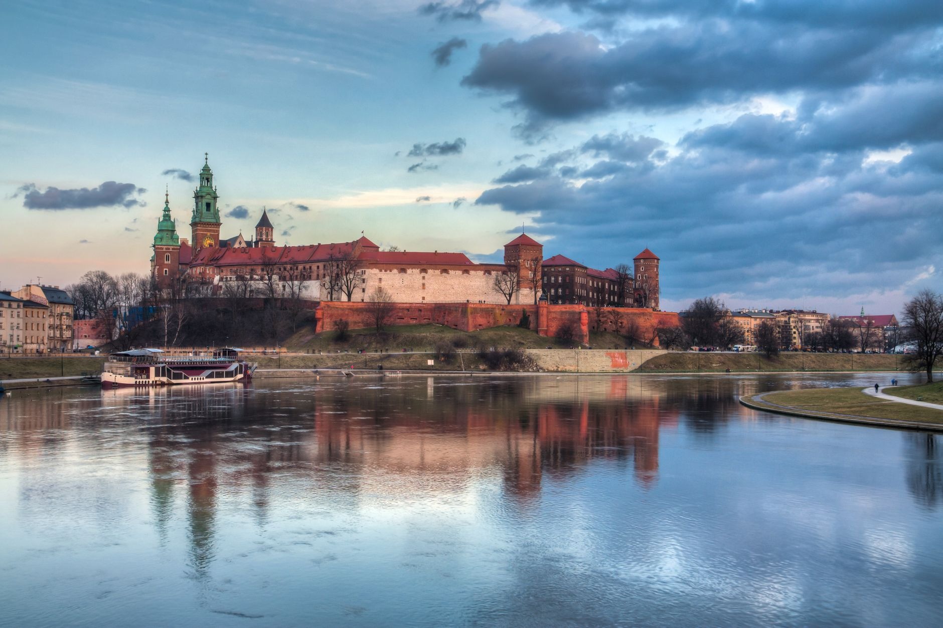 Fortified brick walls and Renaissance towers of Wawel Royal Castle rising above the Vistula River in Krakow