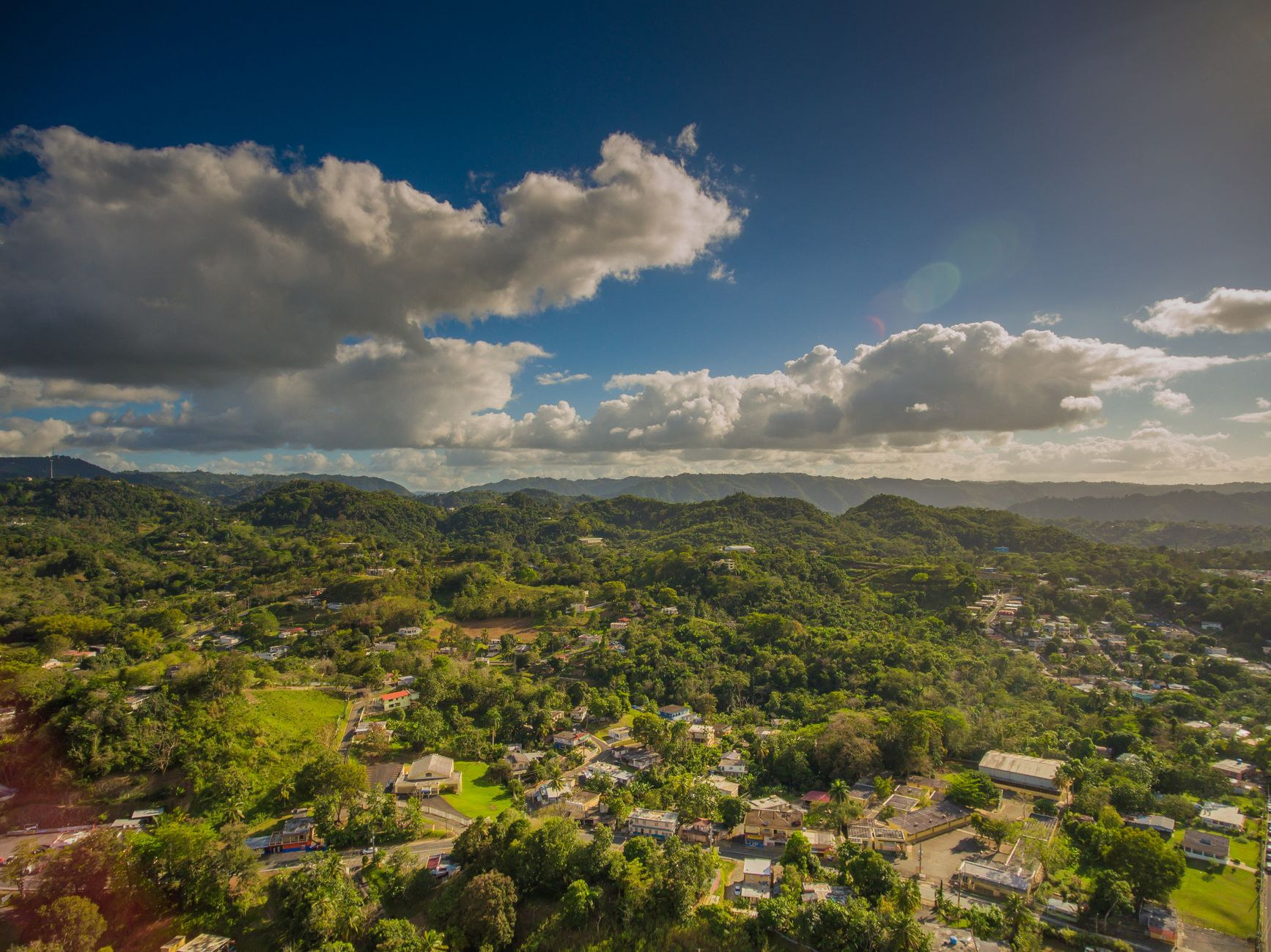 Rolling green forested mountain peaks of the Cordillera Central under tropical trade wind clouds
