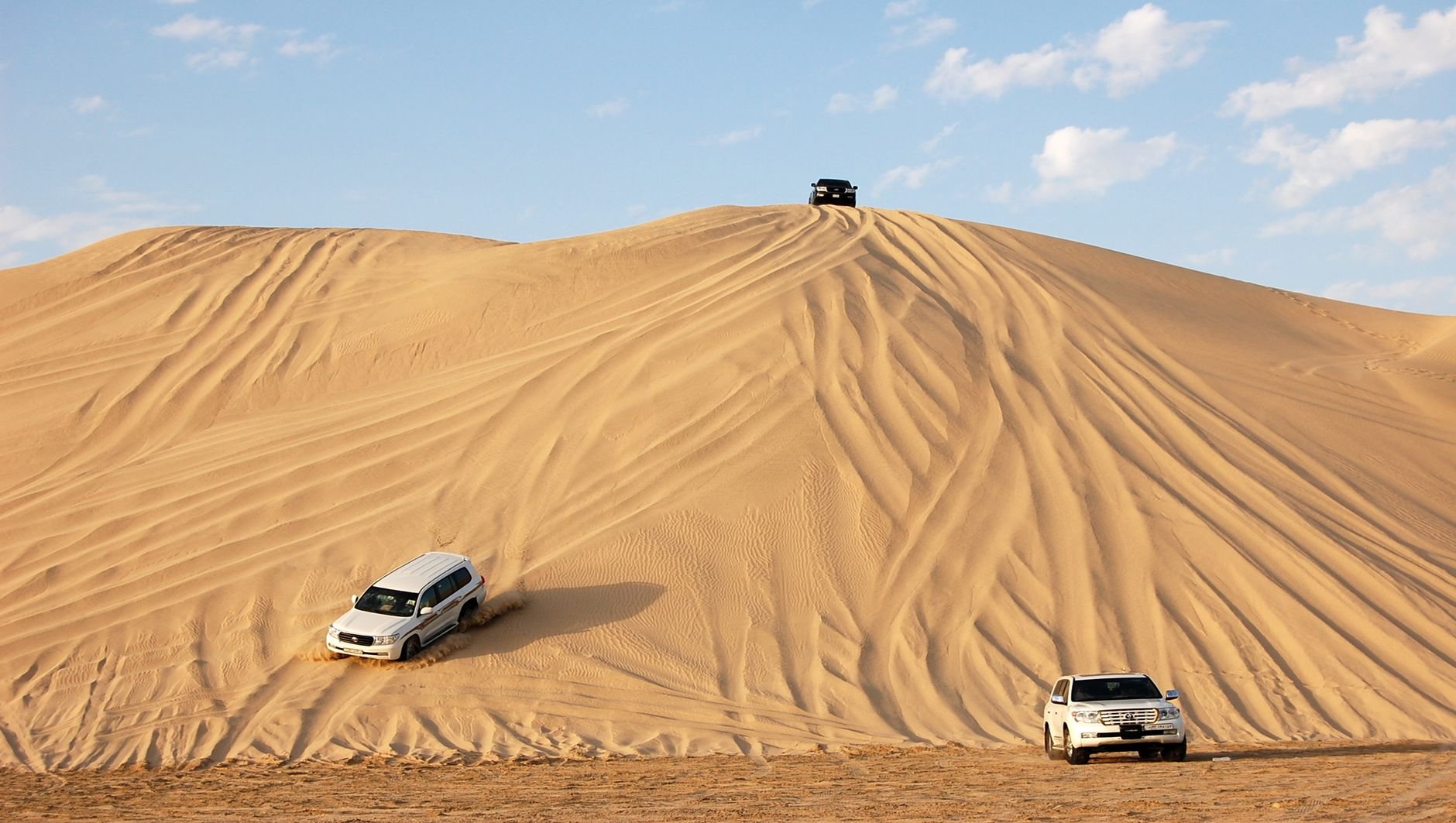 Towering desert sand dunes rolling directly into the azure tidal waters of the Khor Al Adaid Inland Sea near the Saudi border