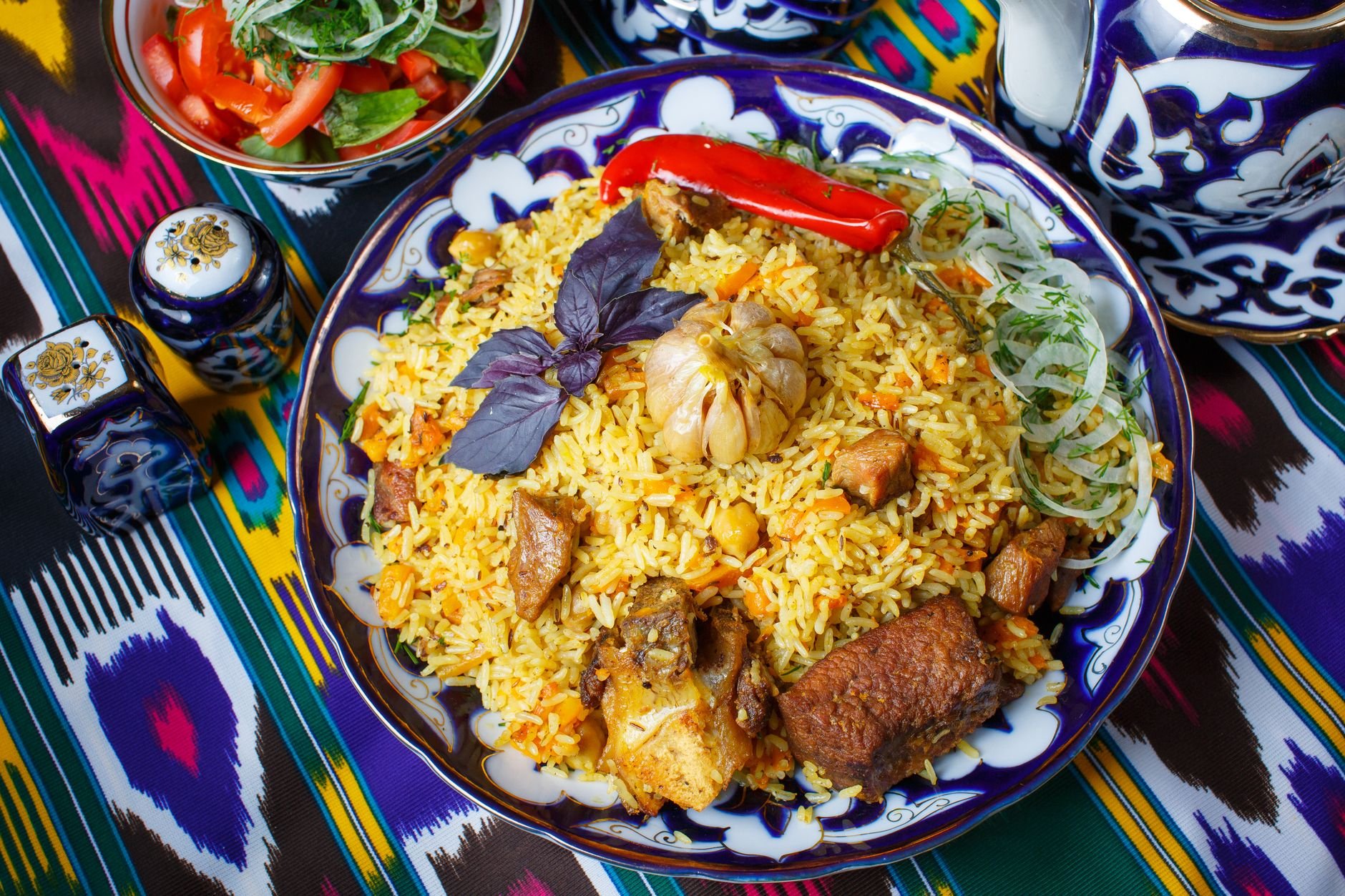 Aromatic platter of Qatari machboos spiced basmati rice topped with tender slow-cooked roasted meat, pine nuts, and dried black lime