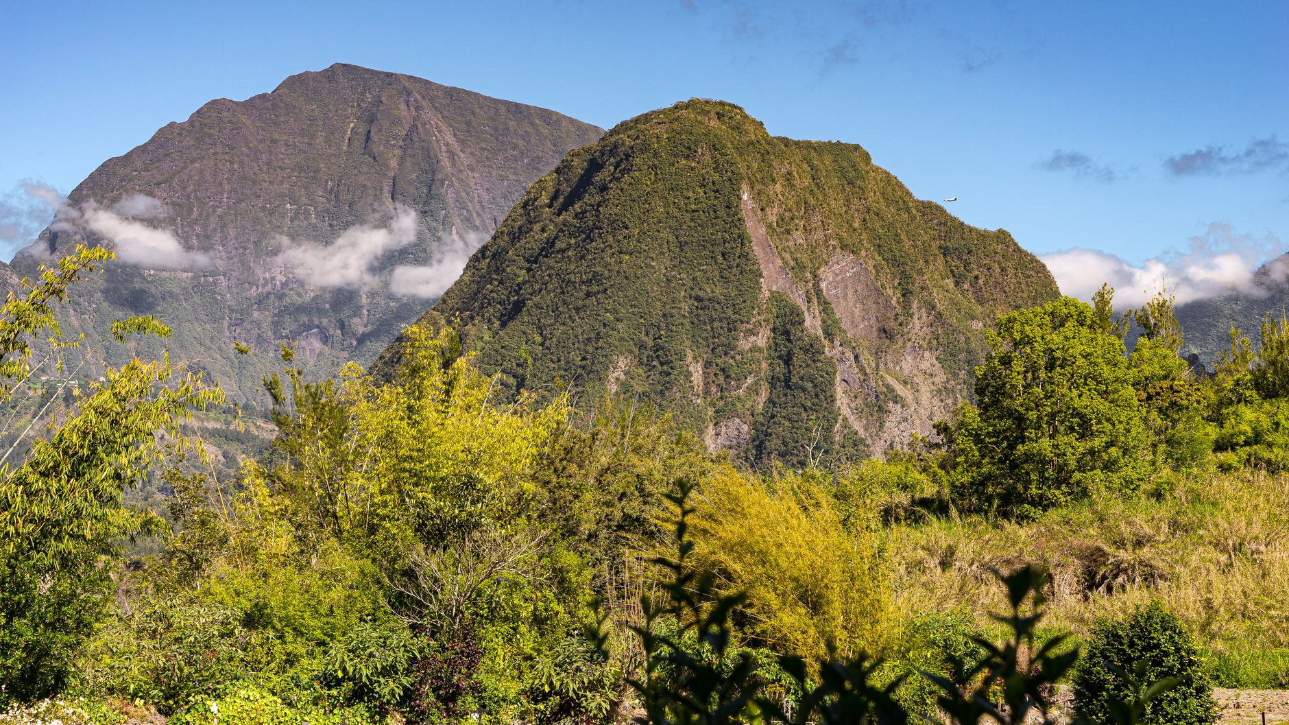 Lush subtropical green vegetation and steep vertical cliff walls framing the natural amphitheater of Cirque de Cilaos