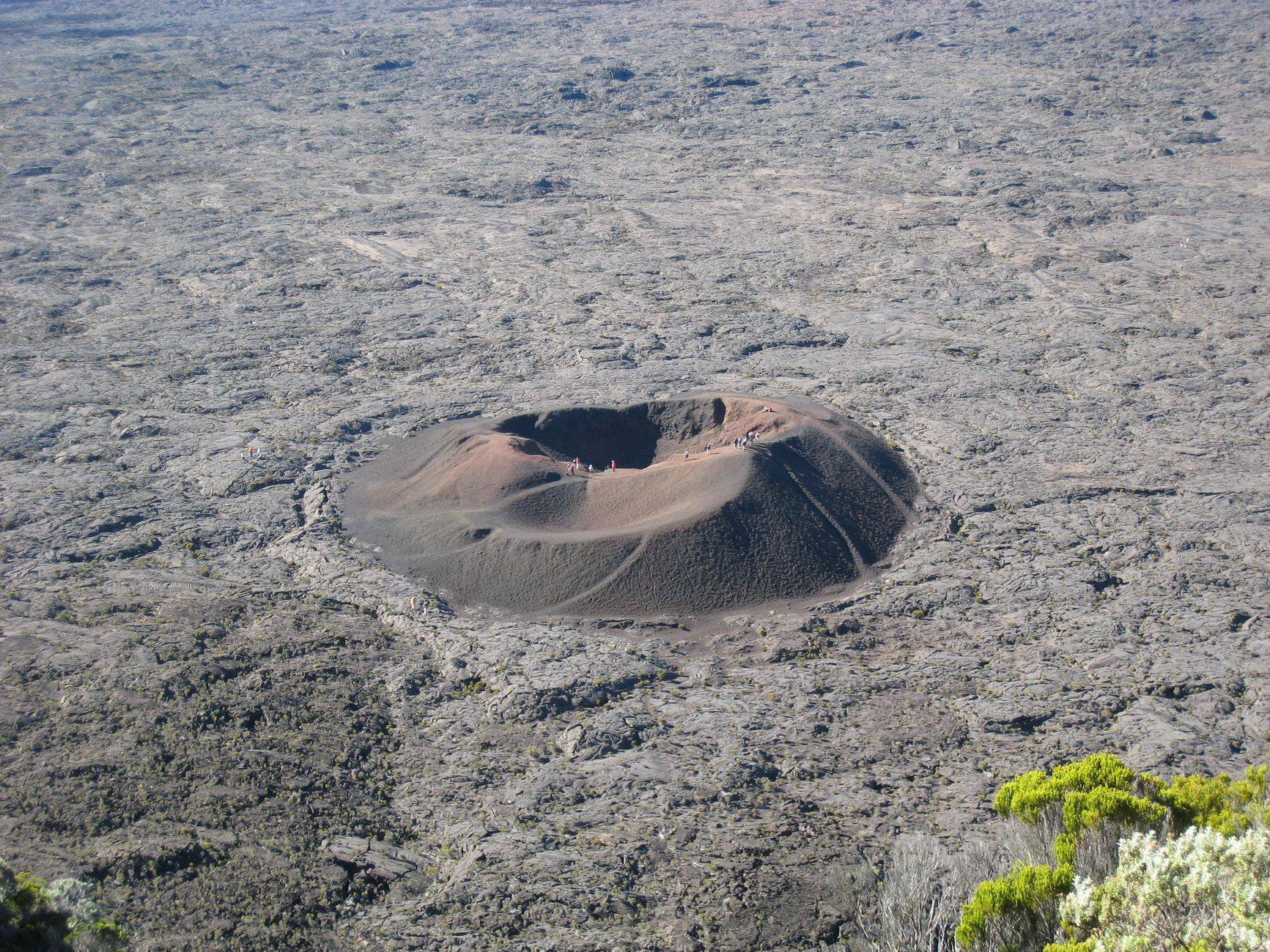 Aerial perspective of the reddish-brown Formica Léo cinder cone crater inside the Enclos Fouqué caldera on Réunion Island